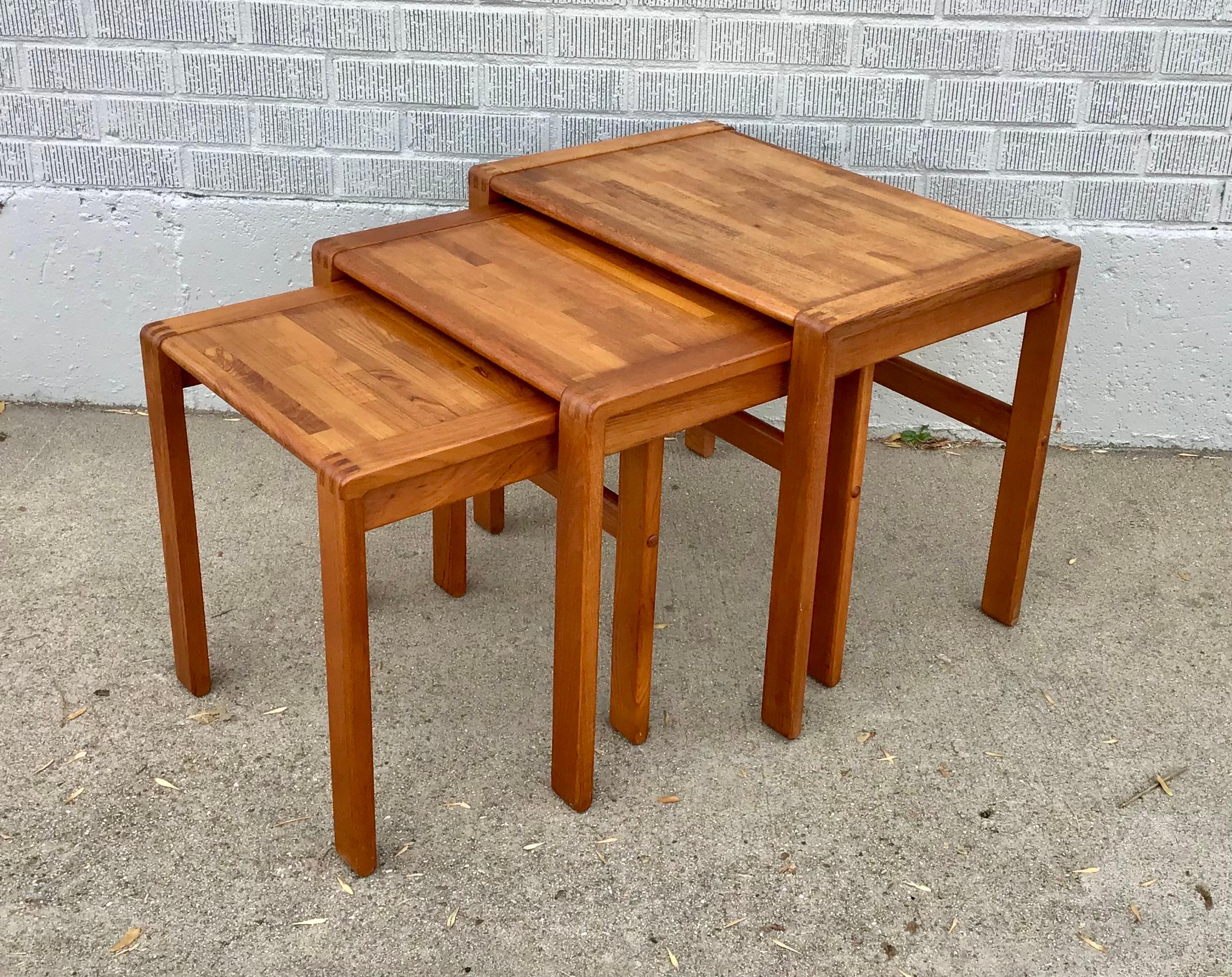 A handsome set of three mid-century modern teak nesting tables marked 