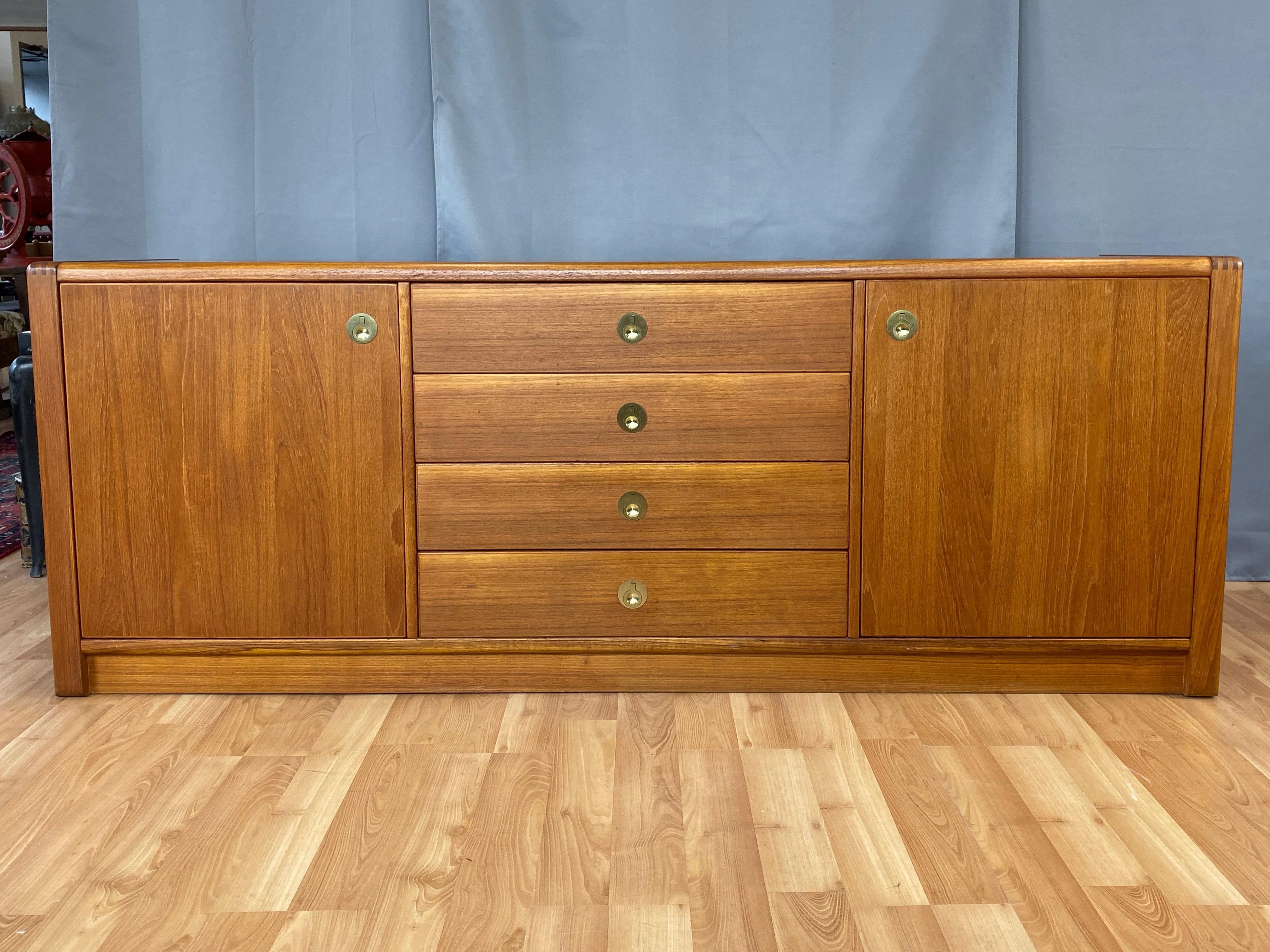 A large 1970s Scandinavian Modern Captain Line teak credenza or dresser by D-Scan.

Expansive piece offers ample storage, with four drawers and two cabinets with adjustable shelves. In addition to handsomely figured teak veneer throughout, it