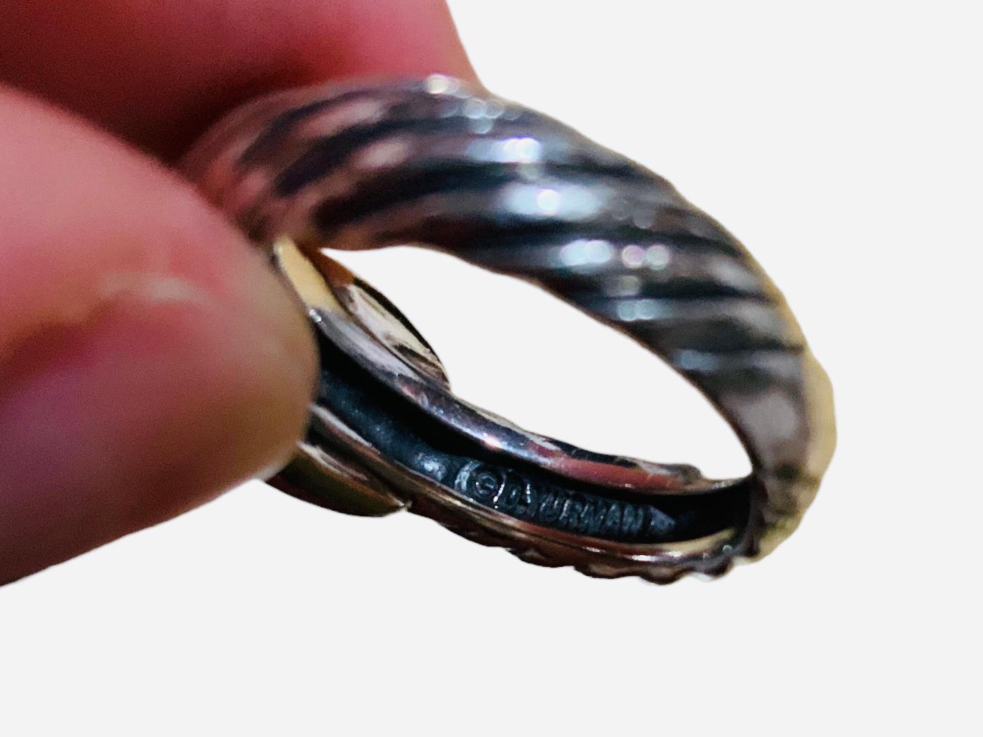 This is a 585 ( 14K ) gold and 925 sterling silver ring. It depicts a wide silver rope like band adorned with two crossed  wide ribbons in the center. It is hallmarked D.Yurman. It is also inscribed 925 and 585 inside the shank of the ring.