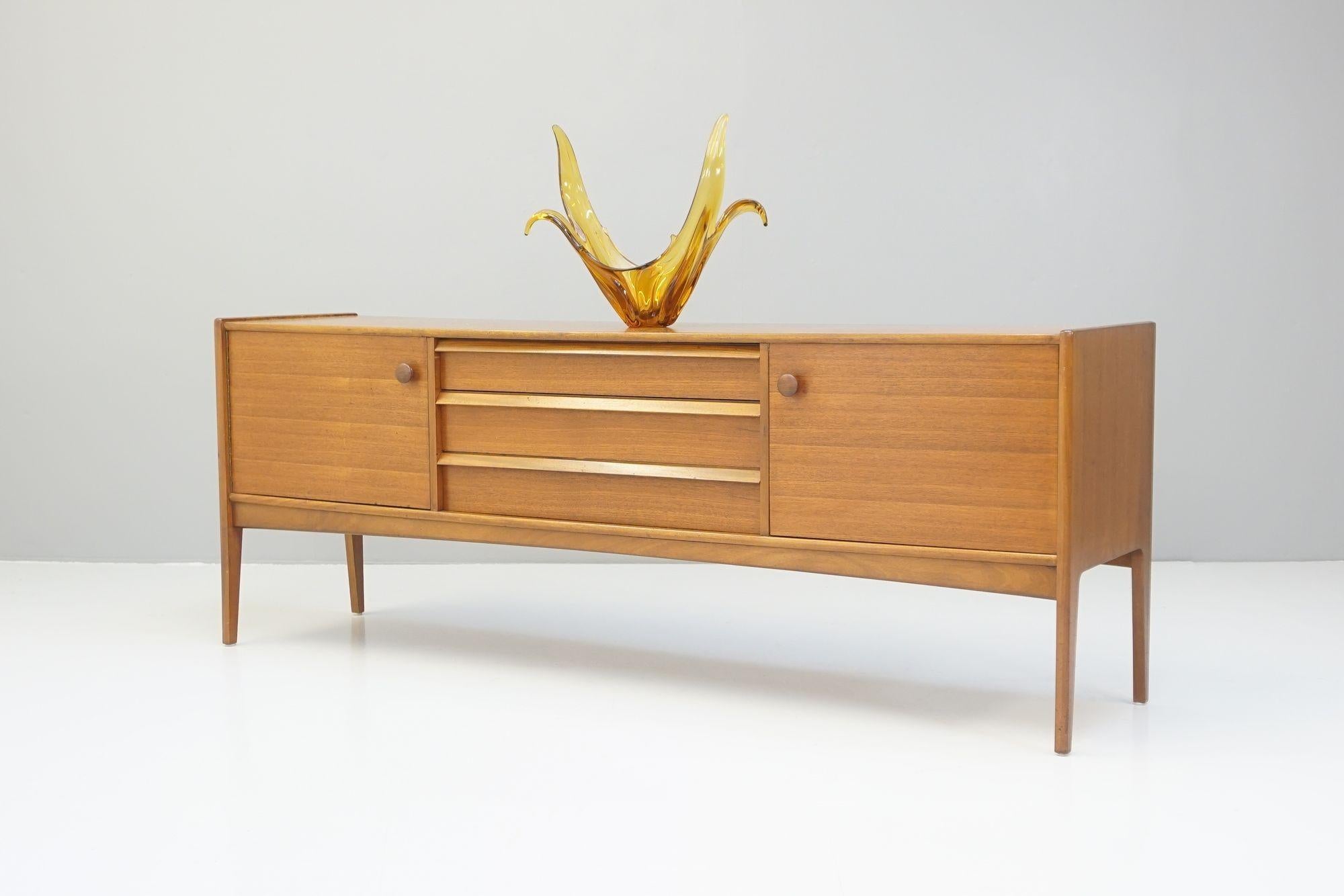 Credenza in Teak massiccio di A Younger con tre cassetti affiancati da due armadi a ripiani. Completamente restaurato, ottime condizioni generali.
