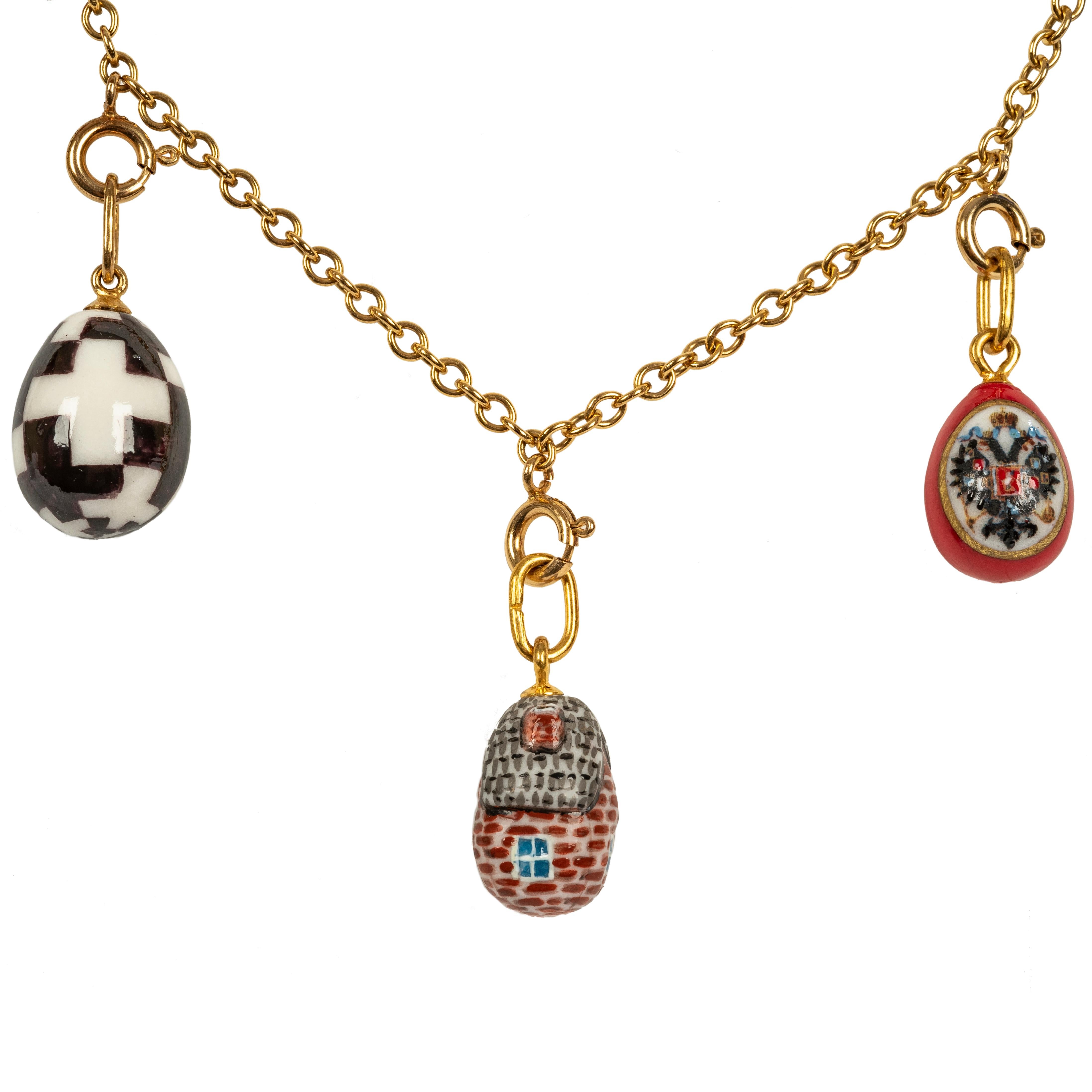 Designed as a classic link chain suspending nine hand painted egg pendants from St. Petersburg, Russia. 

In colorful porcelain depicting a fairy tale dacha with thatched roof, a Romanov double-headed eagle and a landscape of Russian churches among