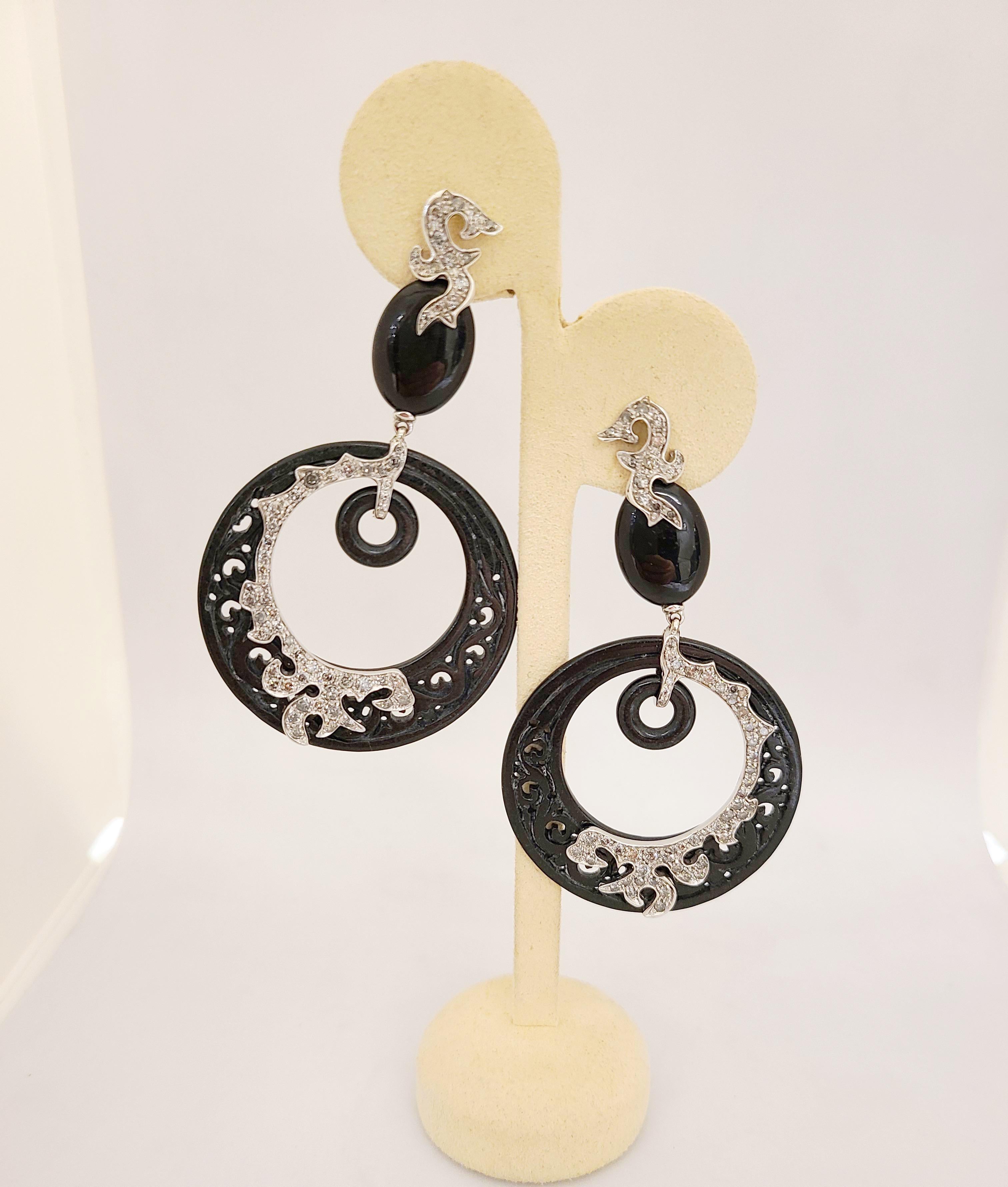 Designed in Italy by Dada Arrigoni these dramatic 18 karat white gold pendant earrings make a bold statement. The earrings feature large black jade circular pendants with hand carved open scroll work. Grey diamonds set in 18 karat white gold are set