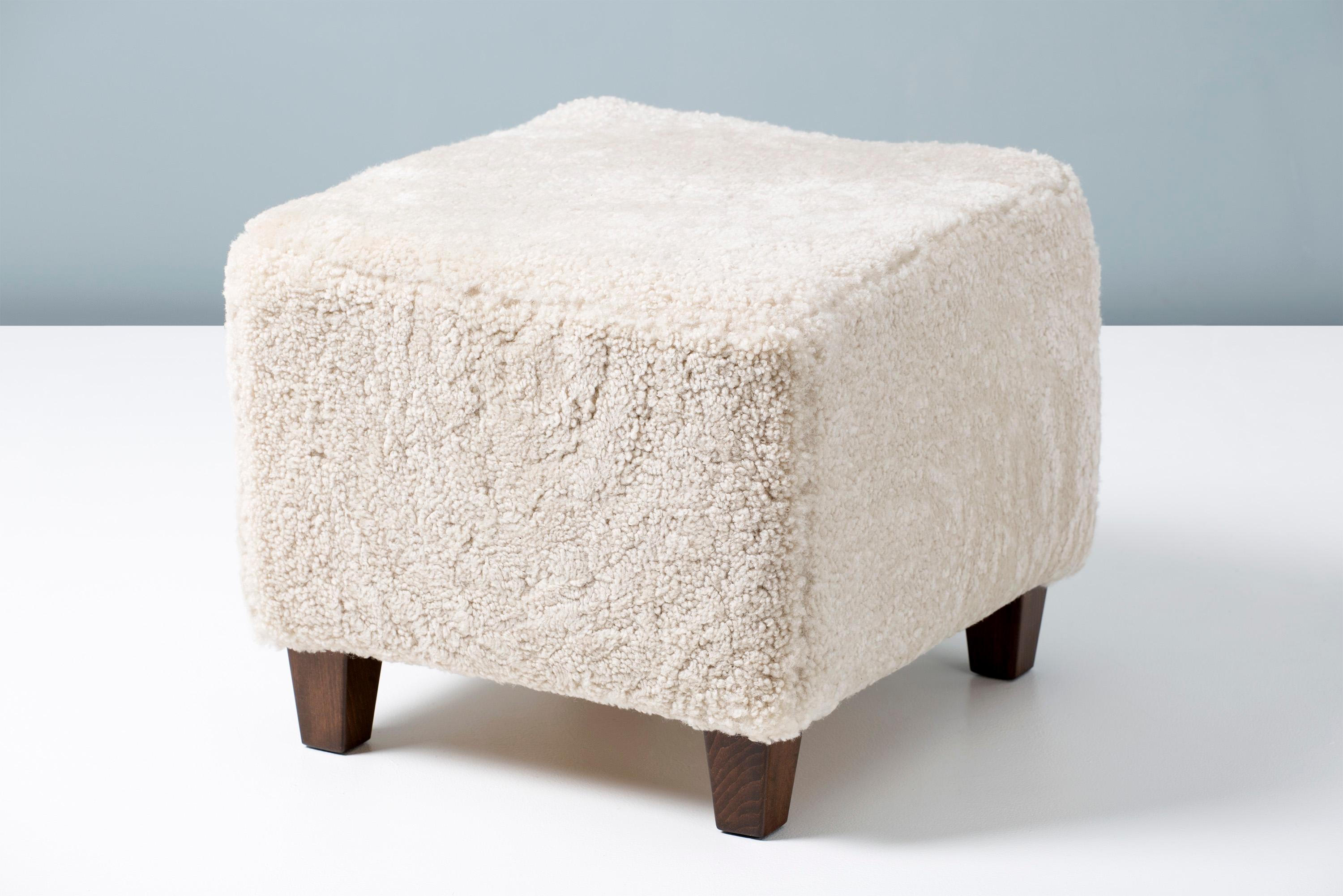 A custom made sheepskin ottoman on hardwood base with stained beech legs. The foam body is covered in premium, tufted Australian shearling. 

This item is made to order in our London workshop, multiple pieces are available by request.