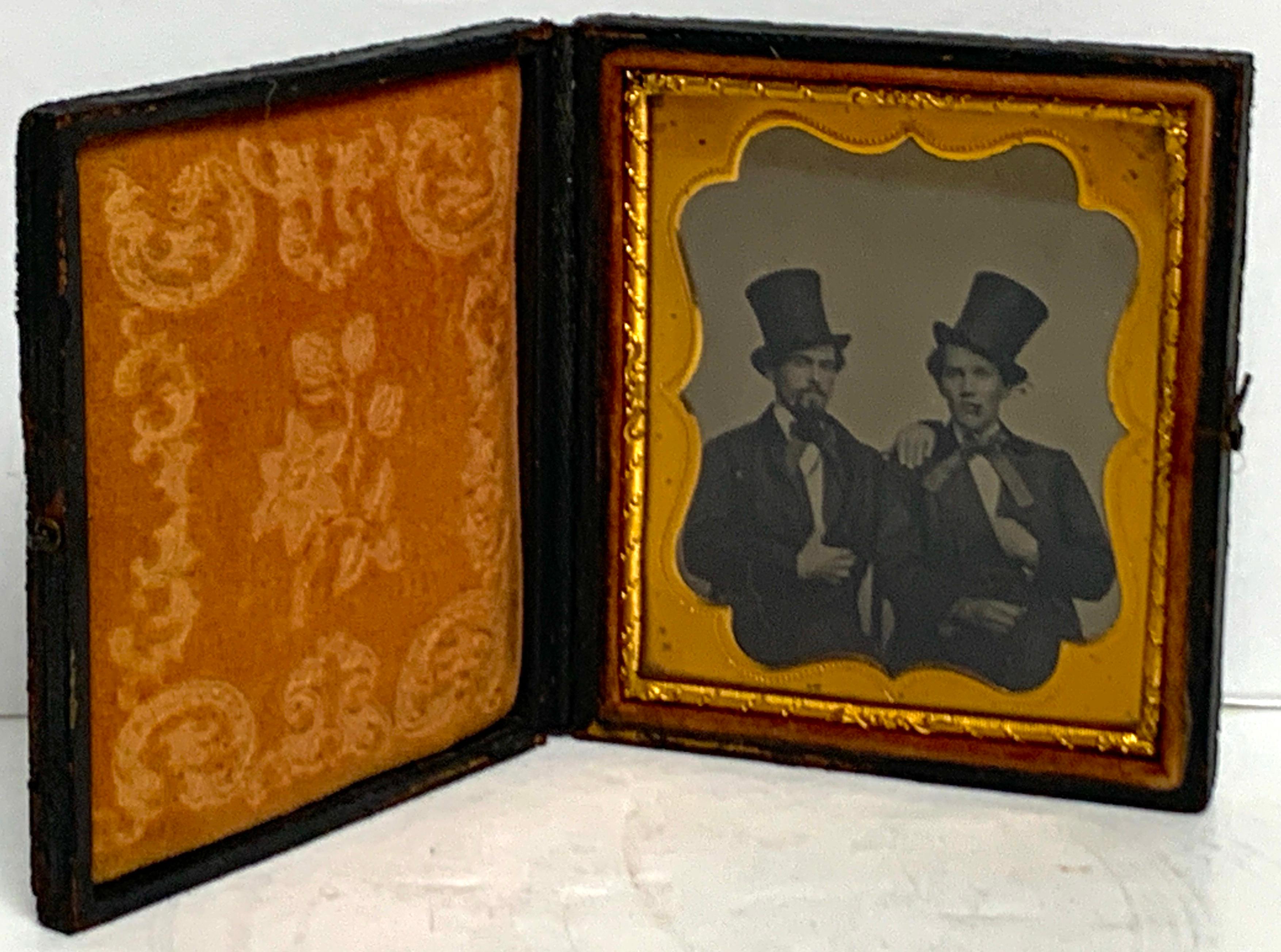 Sixth plate Daguerreotype Portrait of two seated cigar smoking, embracing young men wearing top hats, Western bow ties and , in original pressed-paper/leather case. 
Measures: Case 3.25