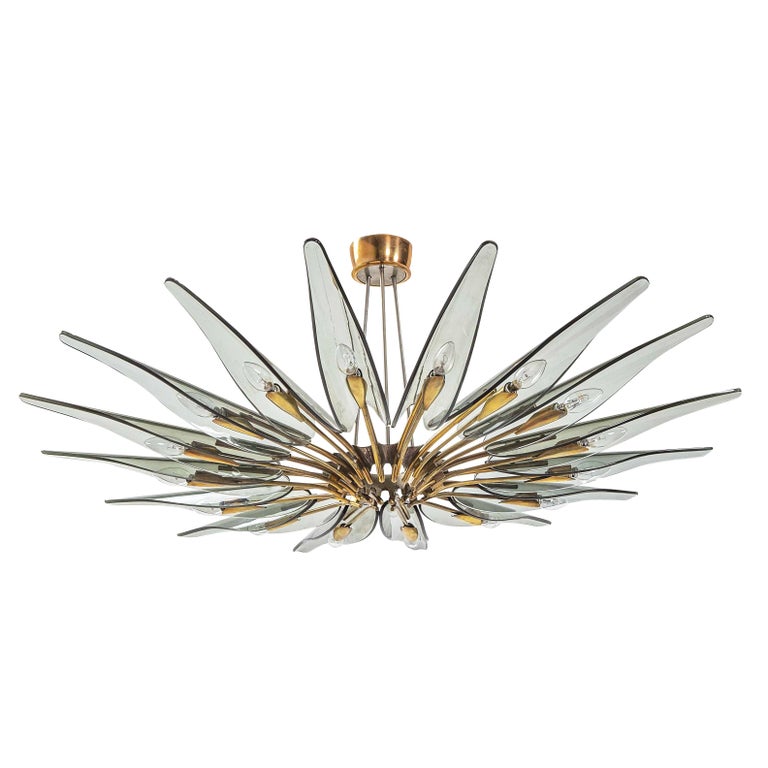 The Dahlia chandelier, Model 1563, designed by Max Ingrand for Fontana Arte in the 1950s is one of the most coveted and iconic pieces of Italian mid-century design. Grey smoked glass petals mounted on a cast brass frame. Holds sixteen candelabra