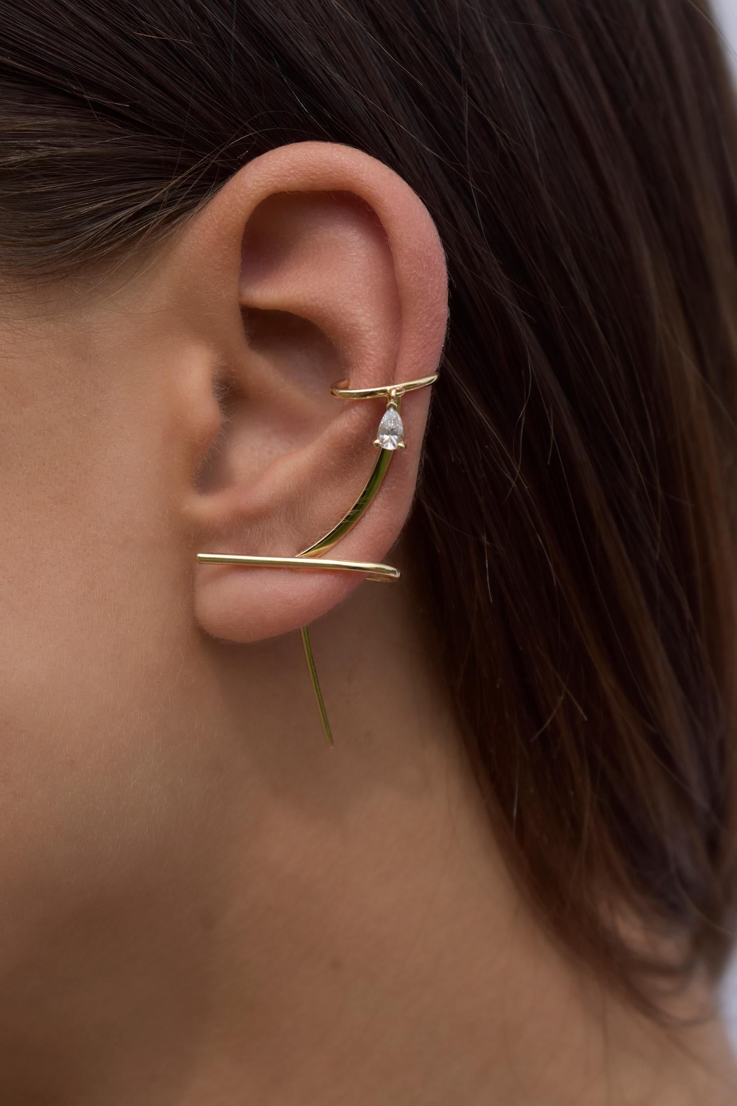 The Daina Cuff Needle Gold Earring is a statement earring in solid 14k gold, featuring a pear shape diamond. It subtle curve follows the outline of your ear finishing in a comfortable cuff with a diamond dangle reflecting the light. 

How to wear