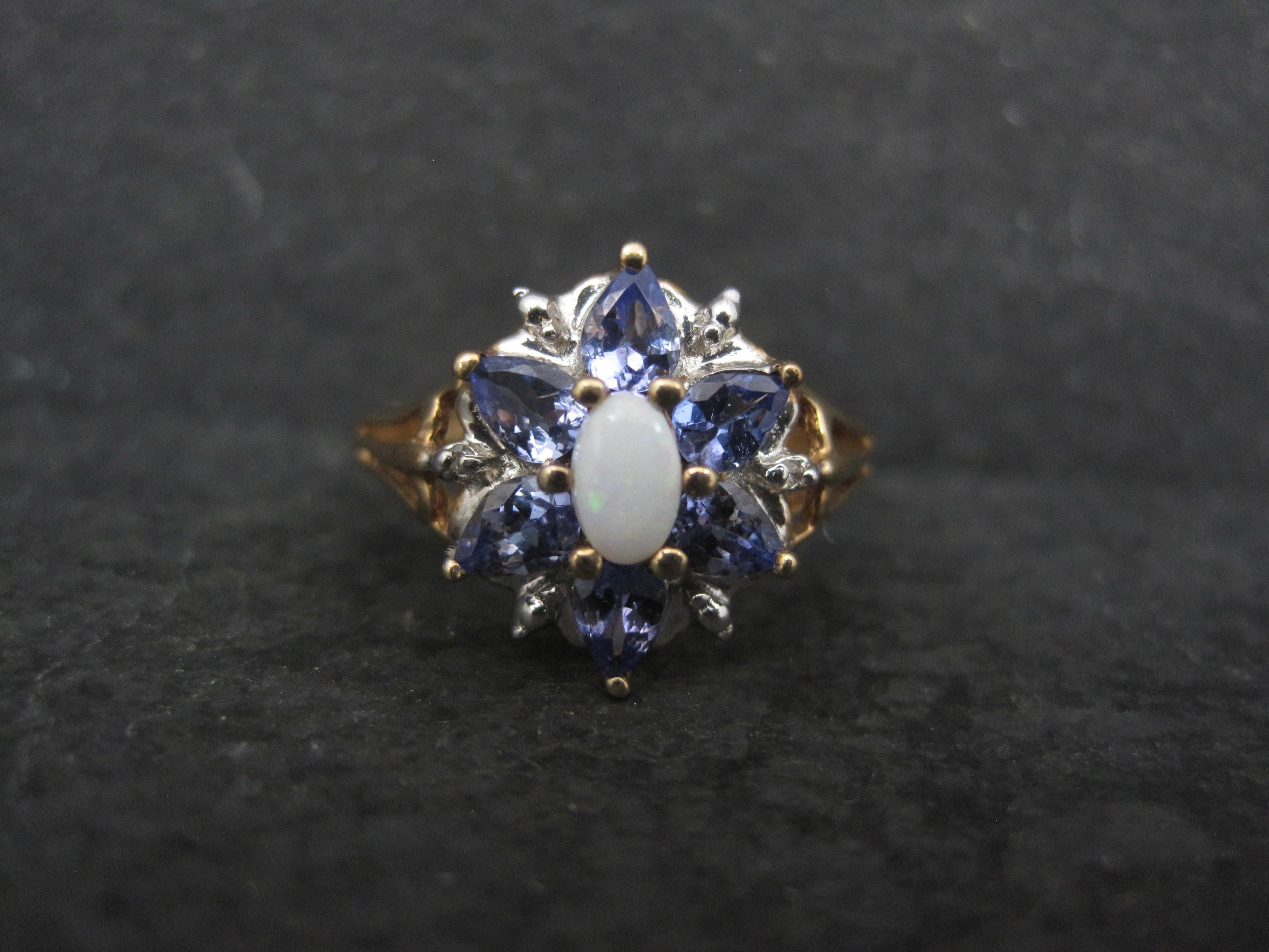 This stunning estate ring features a 3x5 oval cut, white opal accented by 6 pear cut tanzanites.
The face of the ring measures 1/2 inch from knuckle to knuckle.
The ring is 10K yellow gold.
It is a size 7.
It is in excellent overall condition.
