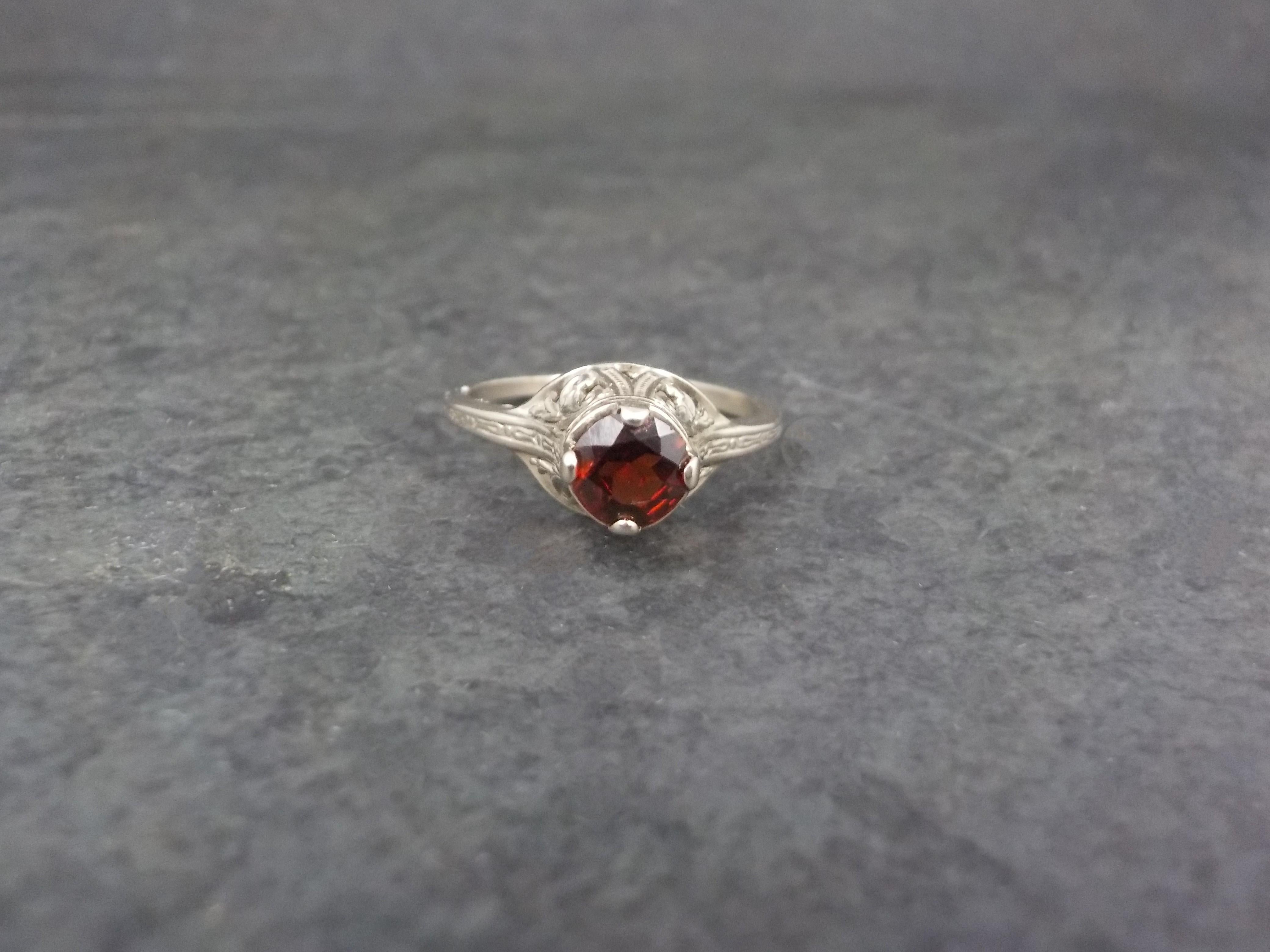This beautiful le style moderne filigree ring is 14k white gold with a natural 5mm garnet gemstone.

The face of this ring measures 1/4 of an inch north to south with a rise of 7mm off the finger.
Size: 4.75
Marks: 14K

Condition: The band shows