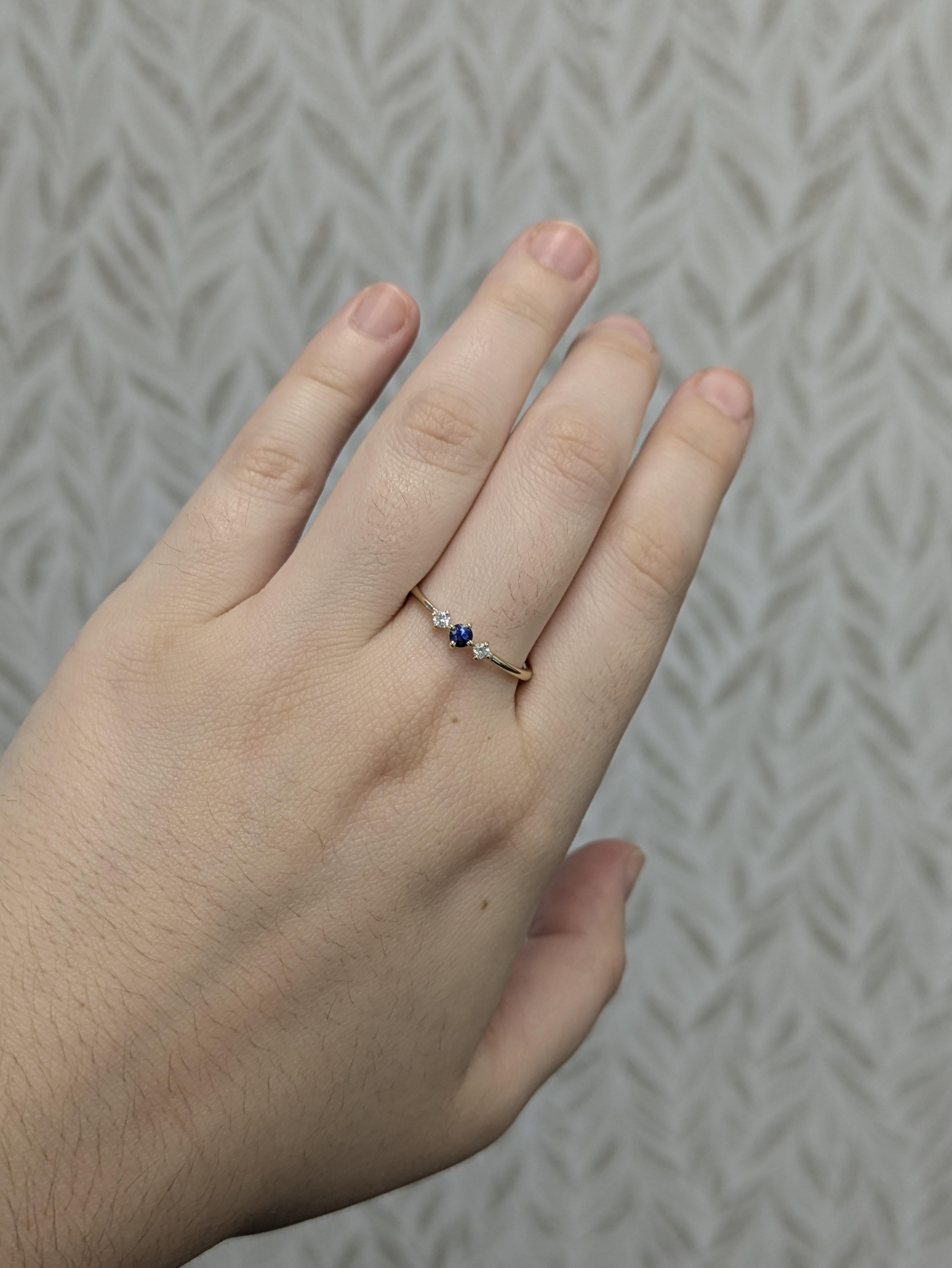 Dieser zarte und zeitlose Ring ist mit einem runden AAA-Ceylon-Saphir von 0,11 Karat (3 mm) besetzt, der für seinen leuchtend blauen Farbton und seine feine Qualität bekannt ist. Er ist in 14-karätigem Gold (1,3 g) gefasst und wird von 2 Diamanten