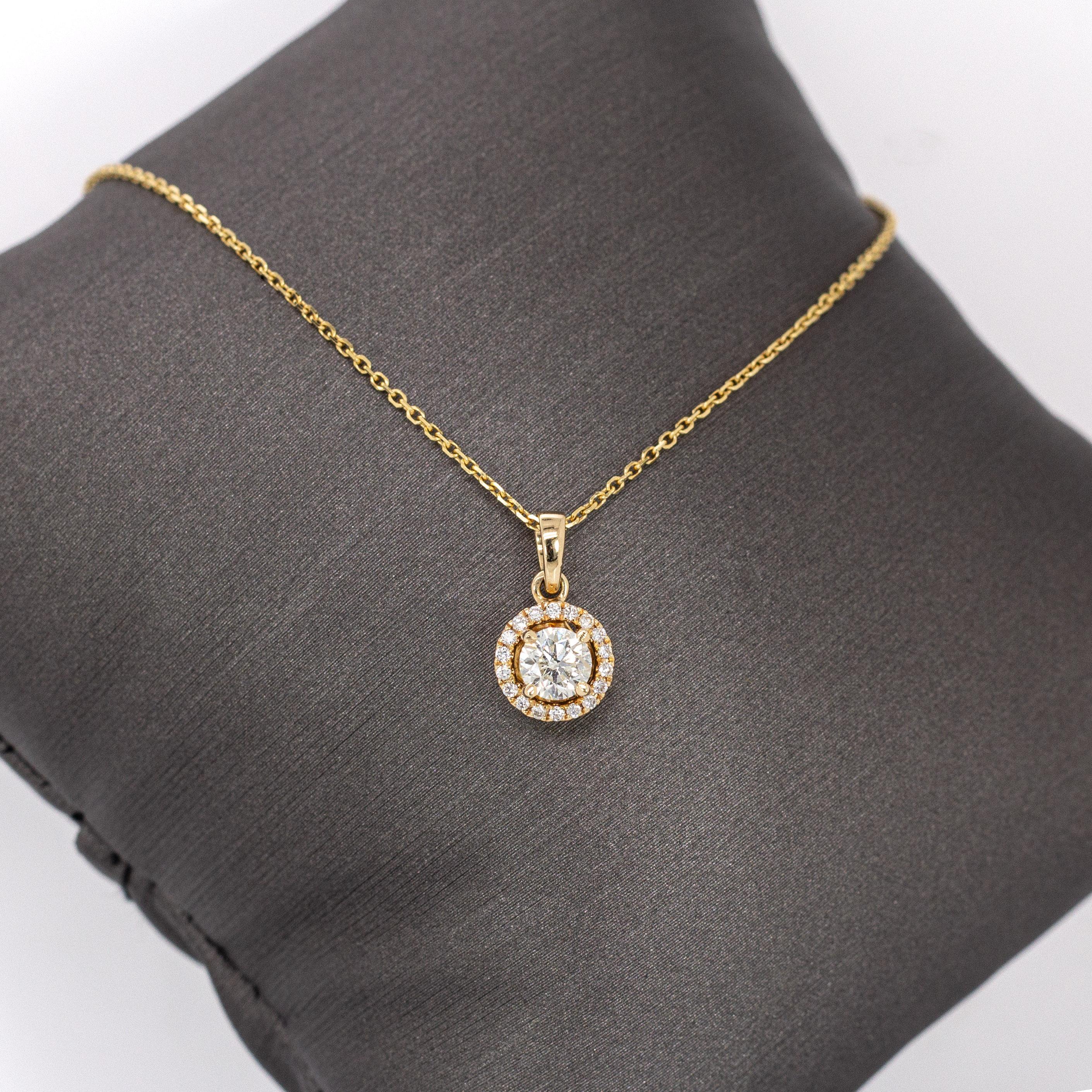 This dainty diamond pendant captures the essence of minimalist luxury. Featuring a brilliant round center framed by a halo of natural earth-mined diamonds, the design glows in solid 14k yellow gold. A graceful piece she’ll treasure—perfect for