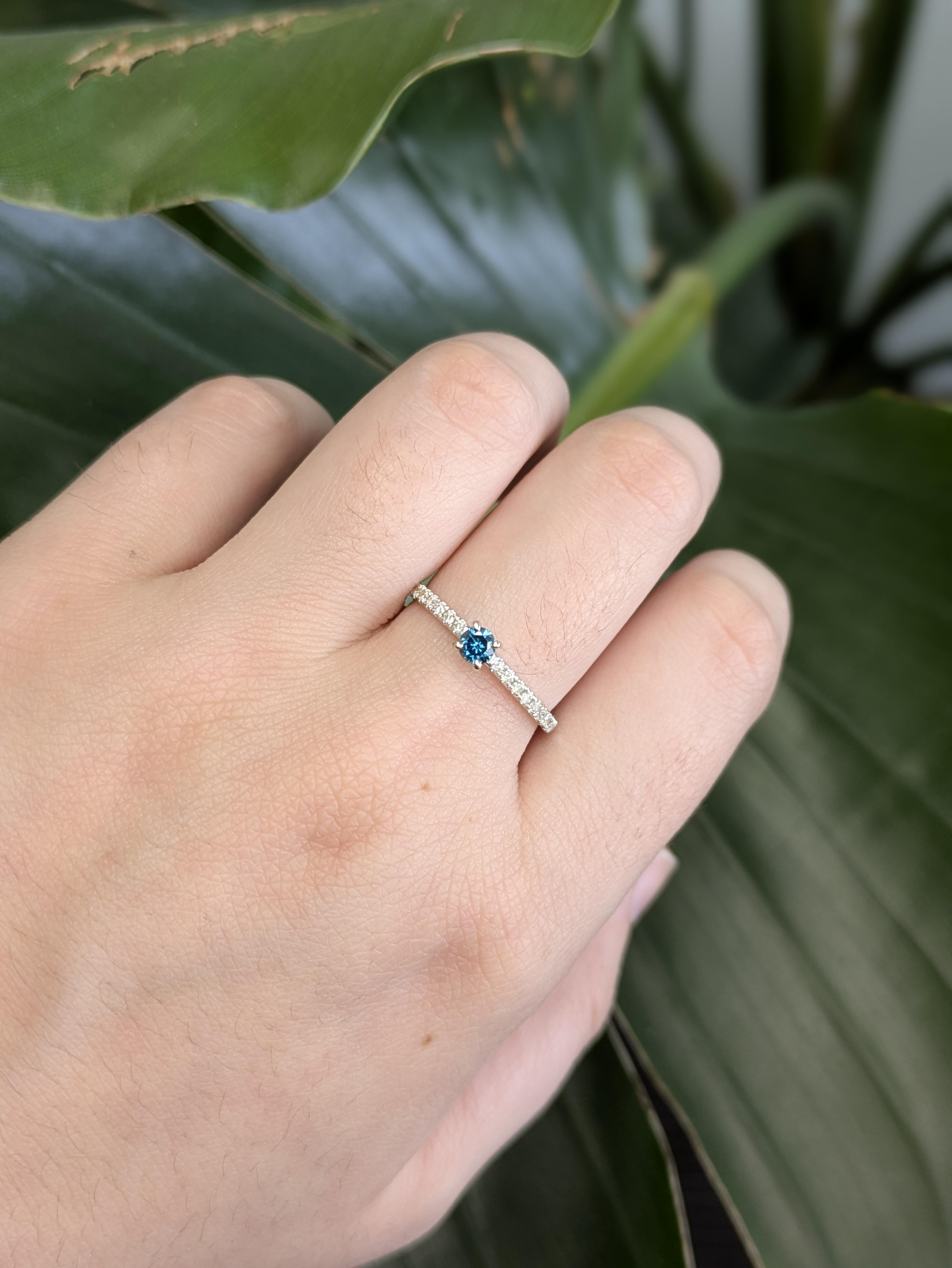 Dieser zarte Ring besticht durch einen runden blauen Diamanten von 0,18 Karat und einer Größe von 3,5 mm, gefasst in glattem 14-karätigem Gold (1,41 g). Der leuchtende Blauton verleiht dem zeitlosen Design eine moderne Note und macht es zu einer