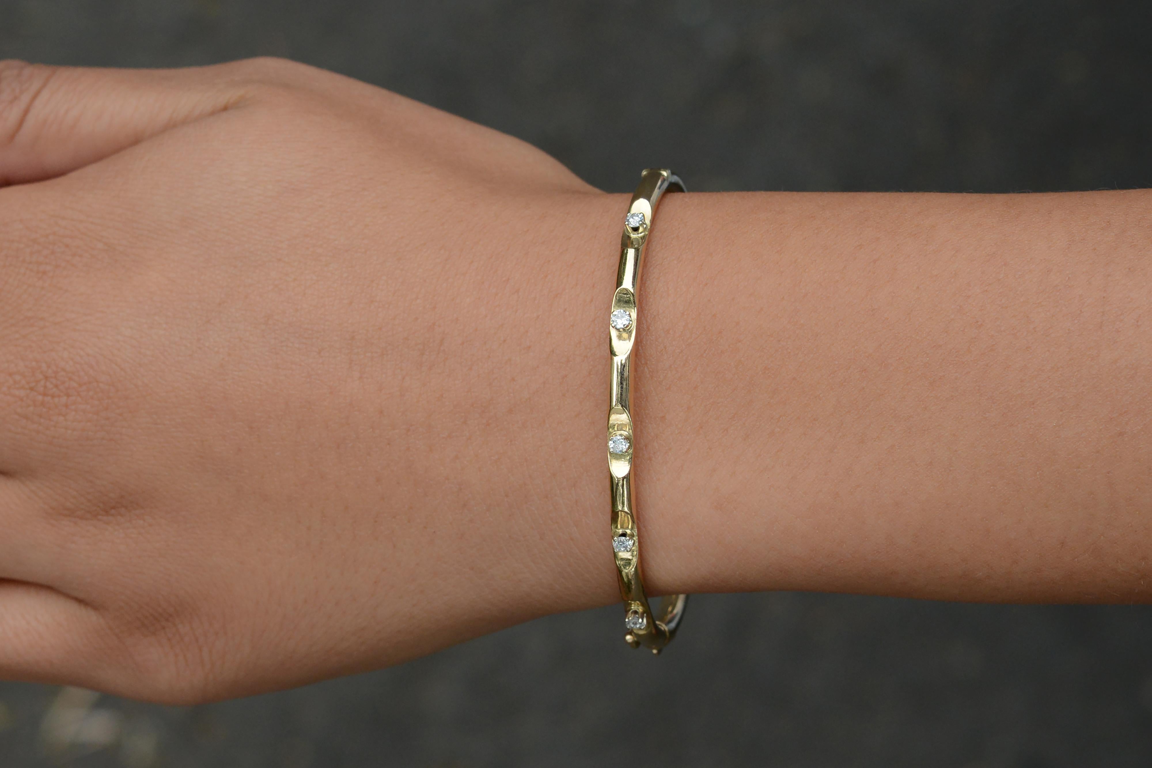 Dieses erschwingliche Vintage-Armband aus 14-karätigem Gelbgold ist mit 5 natürlichen Diamanten besetzt, die in Wellenform gefasst sind. Das Design des Armreifs mit Scharnieren ist perfekt für ein zierliches Handgelenk. Dieses zierliche Stück der