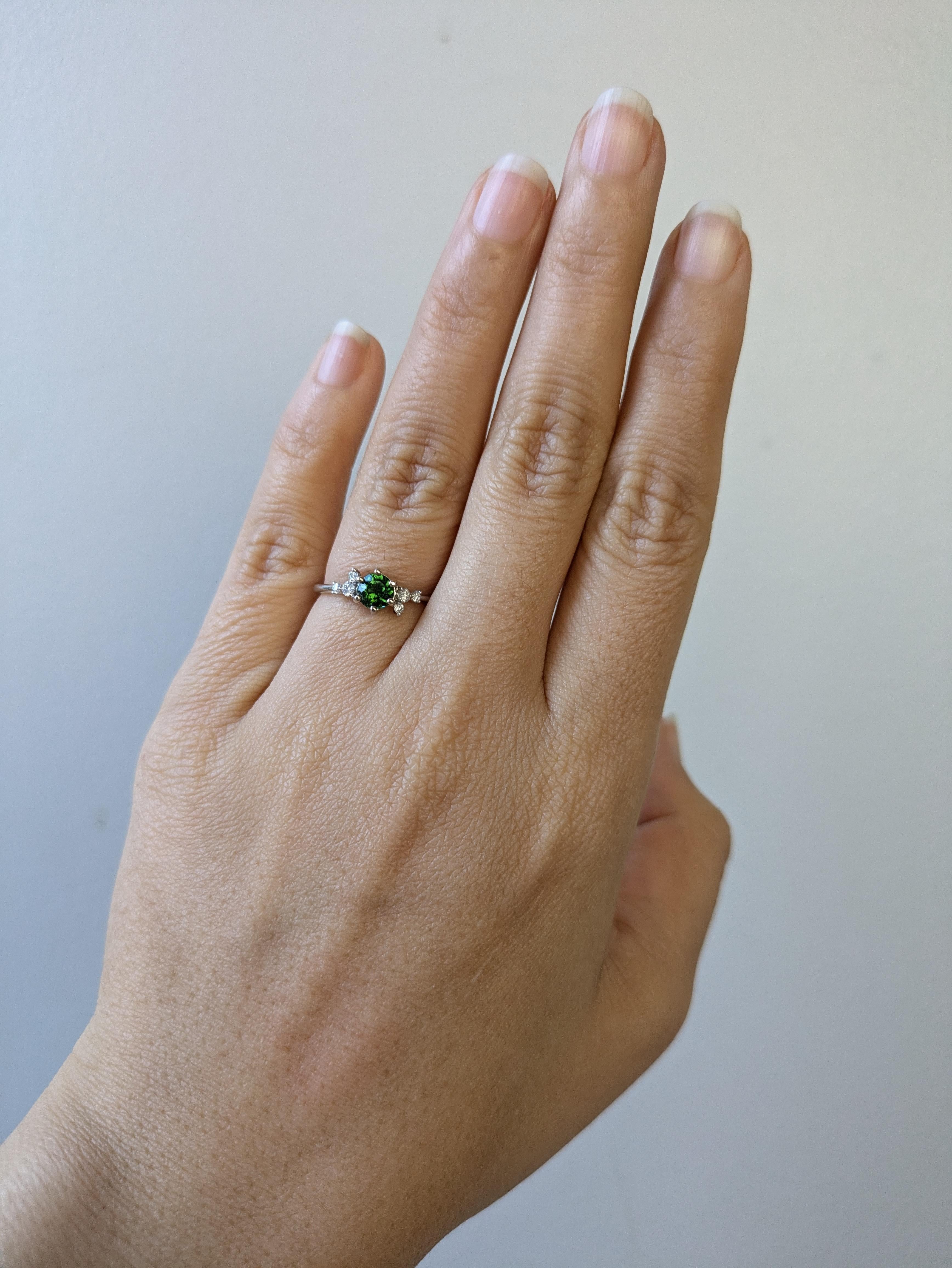 Un anello semplice e delicato, perfetto per il minimalista della tua vita o per regalare a qualcuno il suo primo gioiello :) Questo granato verde presenta una miscela di sfumature verdi perfettamente accentuate dai diamanti su ciascun lato. Il gambo