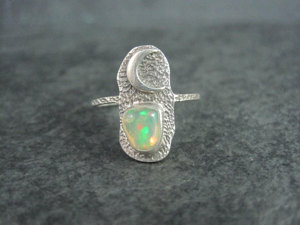 This beautiful, dainty estate ring is sterling silver with an opal gemstone.

The face of this ring measures 3/4 of an inch north to south.
Size: 9

Marks: 925

Condition: Excellent