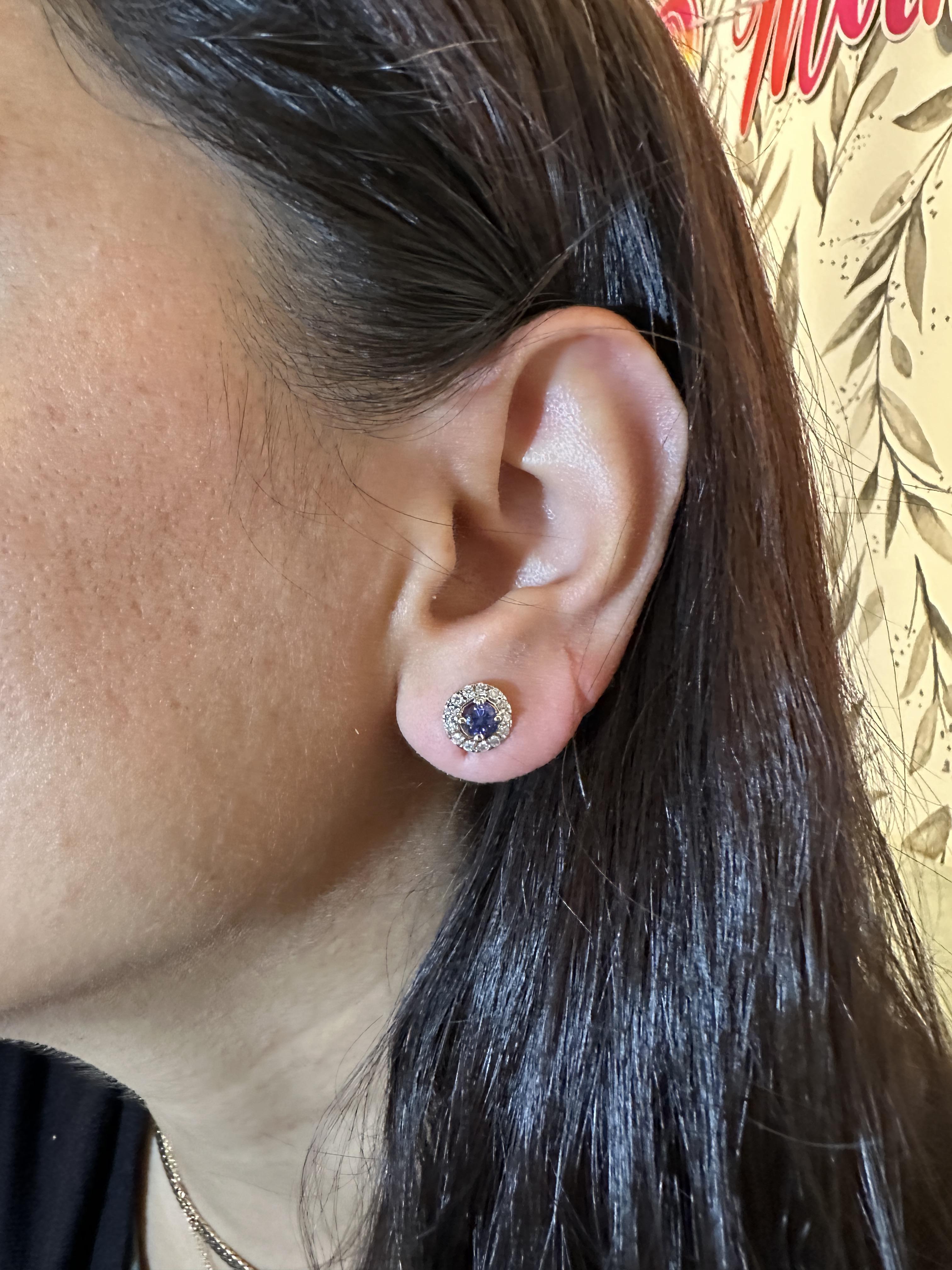 This pair of diamond halo stud earrings feature a matched pair of vibrant blue Tanzanite. A classic earring design perfect for an eye catching anniversary. These earrings also makes a beautiful December birthstone earrings for your loved