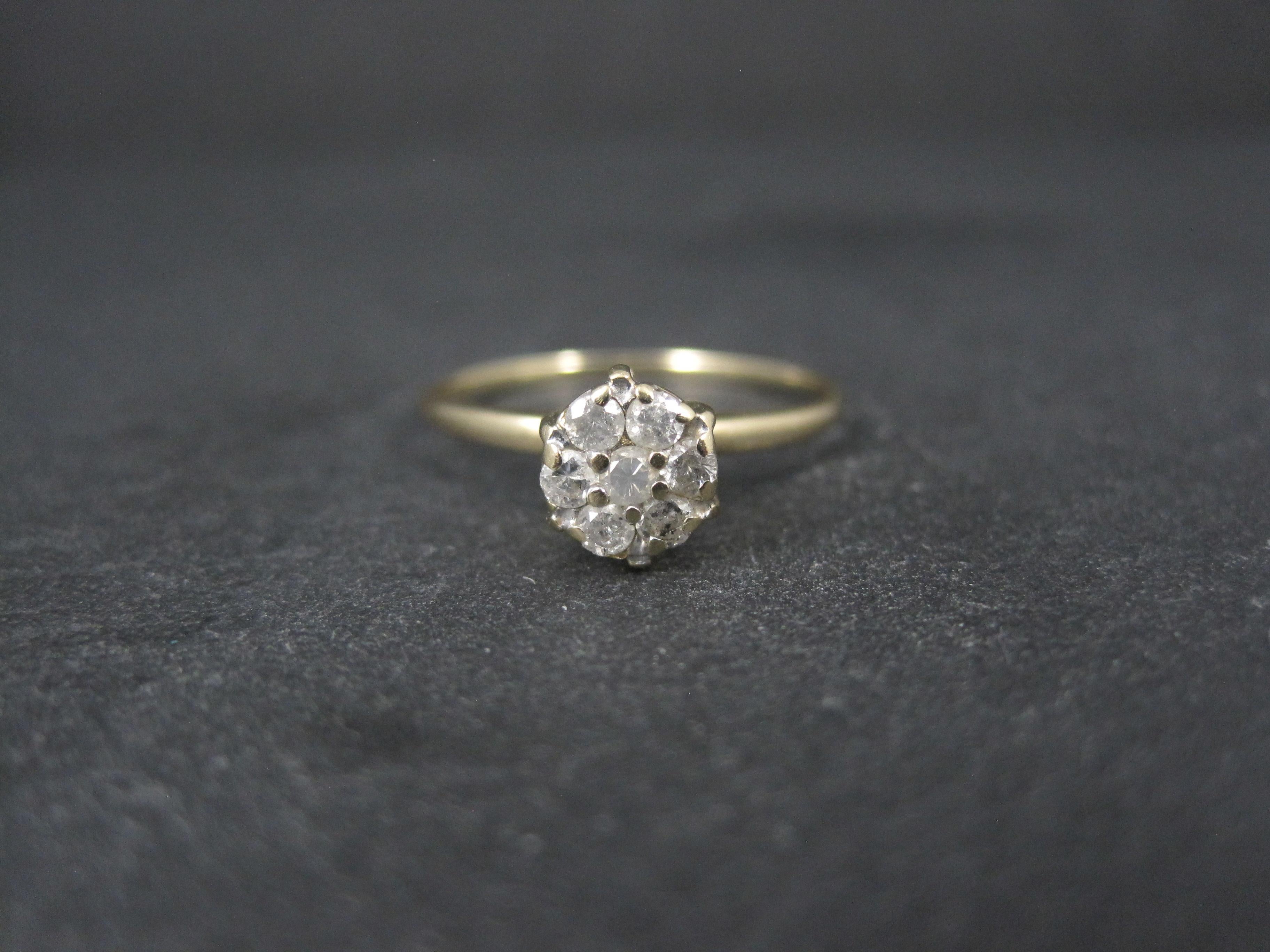 Dieser schöne, zierliche, hoch gefasste Ring im Vintage-Stil ist aus 10 Karat Gold. Es verfügt über eine Gruppe von 7 rund geschliffenen, 3 mm großen Diamanten mit einem geschätzten Wert von 0,21 ctw.
Es sind keine hochwertigen Diamanten, aber es