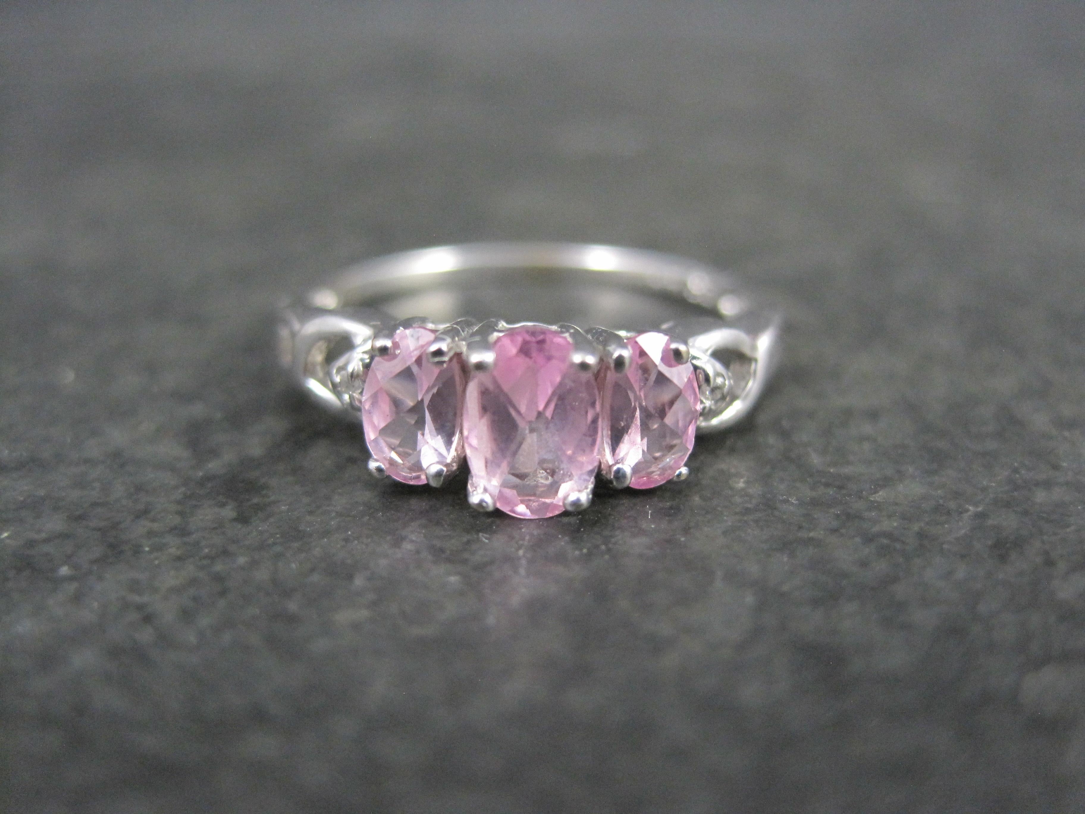 This beautiful, dainty ring is 10K white gold.
It features an estimated .80 carats in oval cut pink topaz and a tiny diamond accent on each side.

The face of this ring measures 1/4 of an inch north to south with a rise of 6mm off the finger.
Size:
