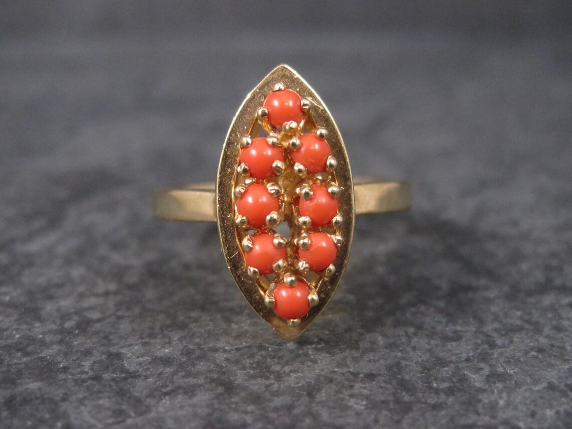 This gorgeous vintage ring is 14k yellow gold.

It features 9 dark coral cabochons.

The face of this ring measures 3/8ths of an inch east to west and 3/4ths of an inch north to south.
The ring has a nice thick band.

It is a size 6.25.

Marks: PL