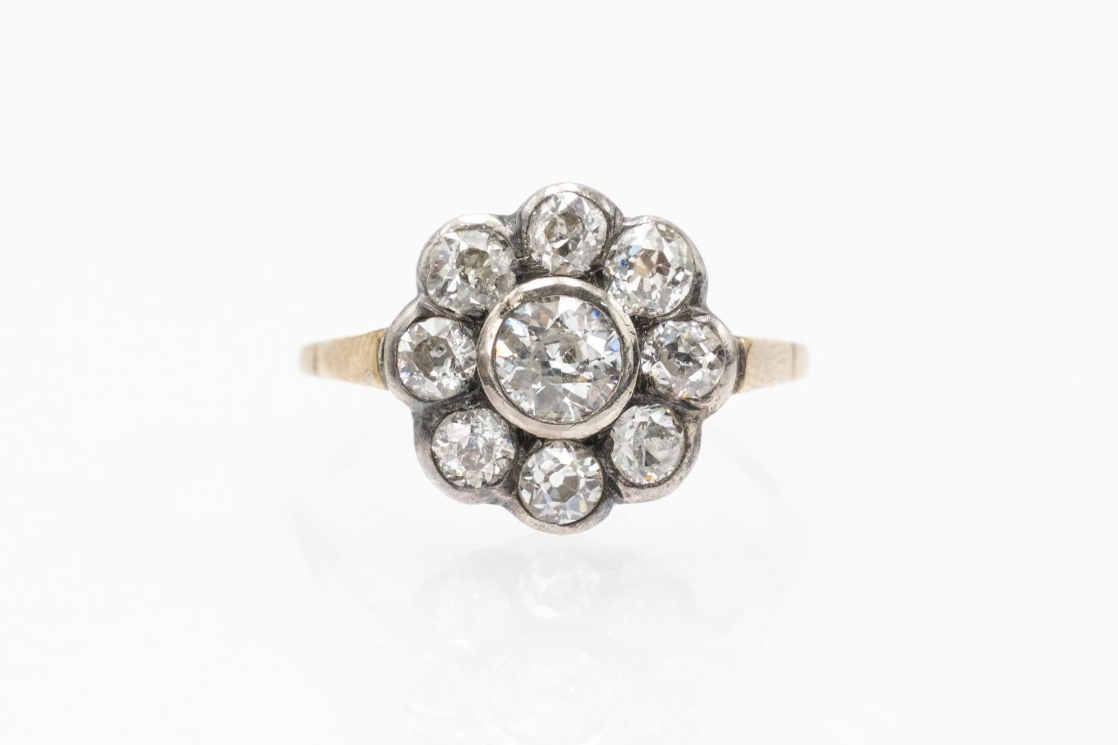 Anello a margherita con vecchi diamanti taglio brillante incastonati in argento sterling tra una delicata fascia di oro giallo a 14 carati (finezza 0,585).

Questo anello antico presenta vecchi diamanti a taglio brillante a forma di fiore, per un