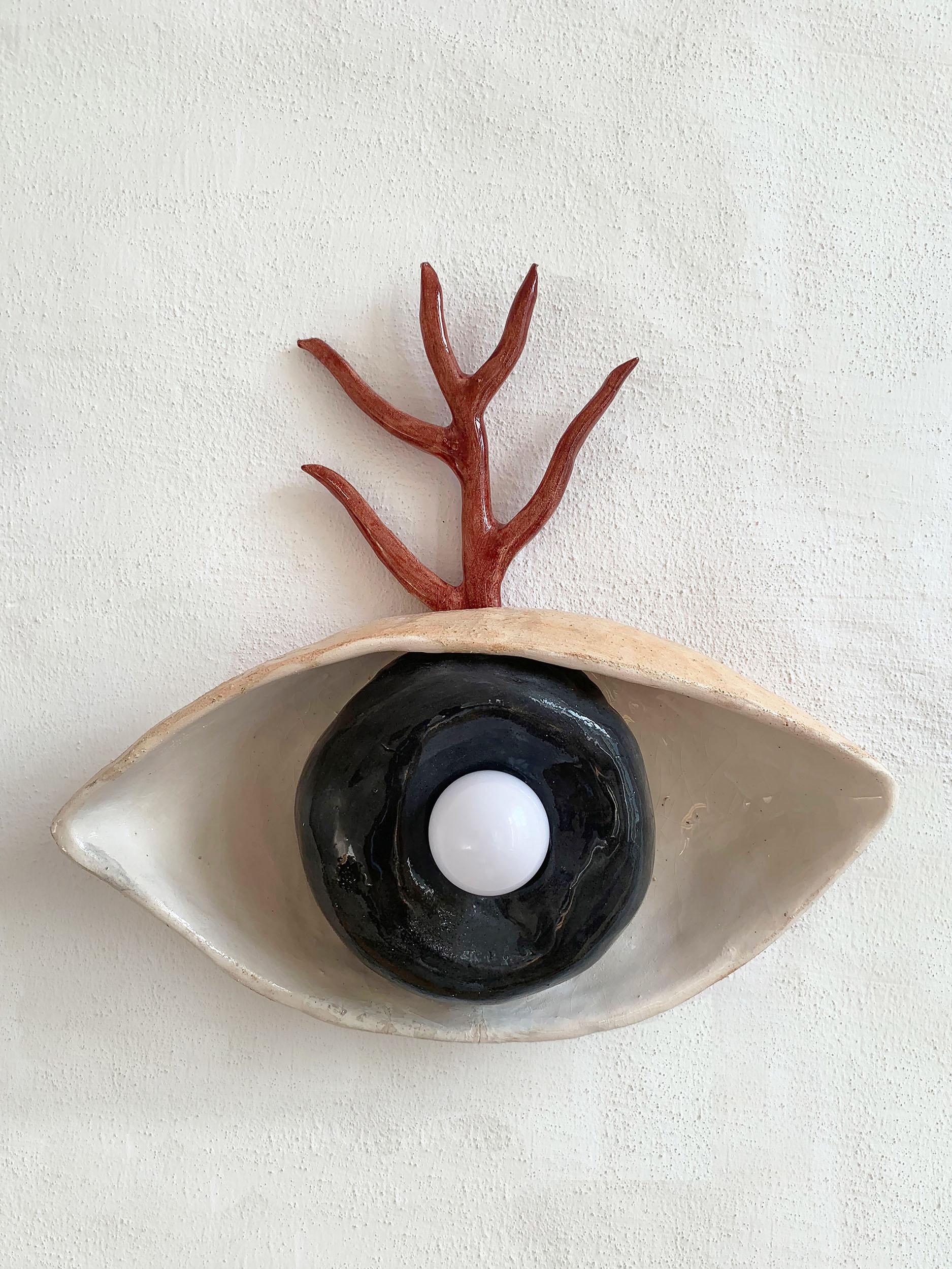 Dal Wall Lamp by Nana Zaalishvili
Dimensions: Ø 30 x H 35 cm.
Materials: Glazed clay.

The wall lamp ‘Dal’ was created under the influence of Svan mythology. The eye symbolizes the most necessary skill for the hunter, while the glazed clay branch