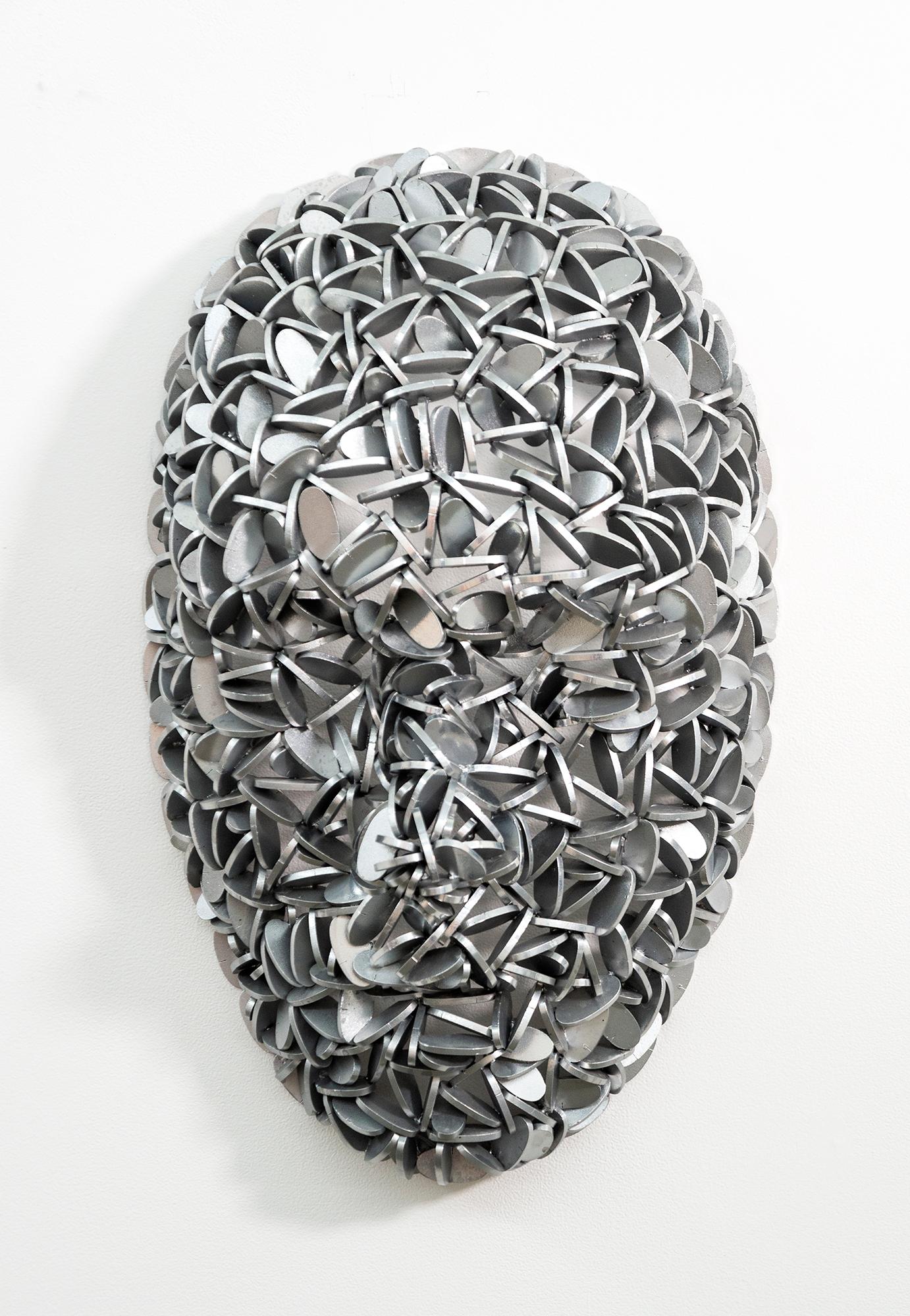 Escultura mural contemporánea de metal en forma de máscara A. El escultor canadiense Dale Dunning utiliza a menudo metales reciclados: esta cabeza con forma humana está fabricada con los centros de piezas de aluminio cepillado cortadas con láser y