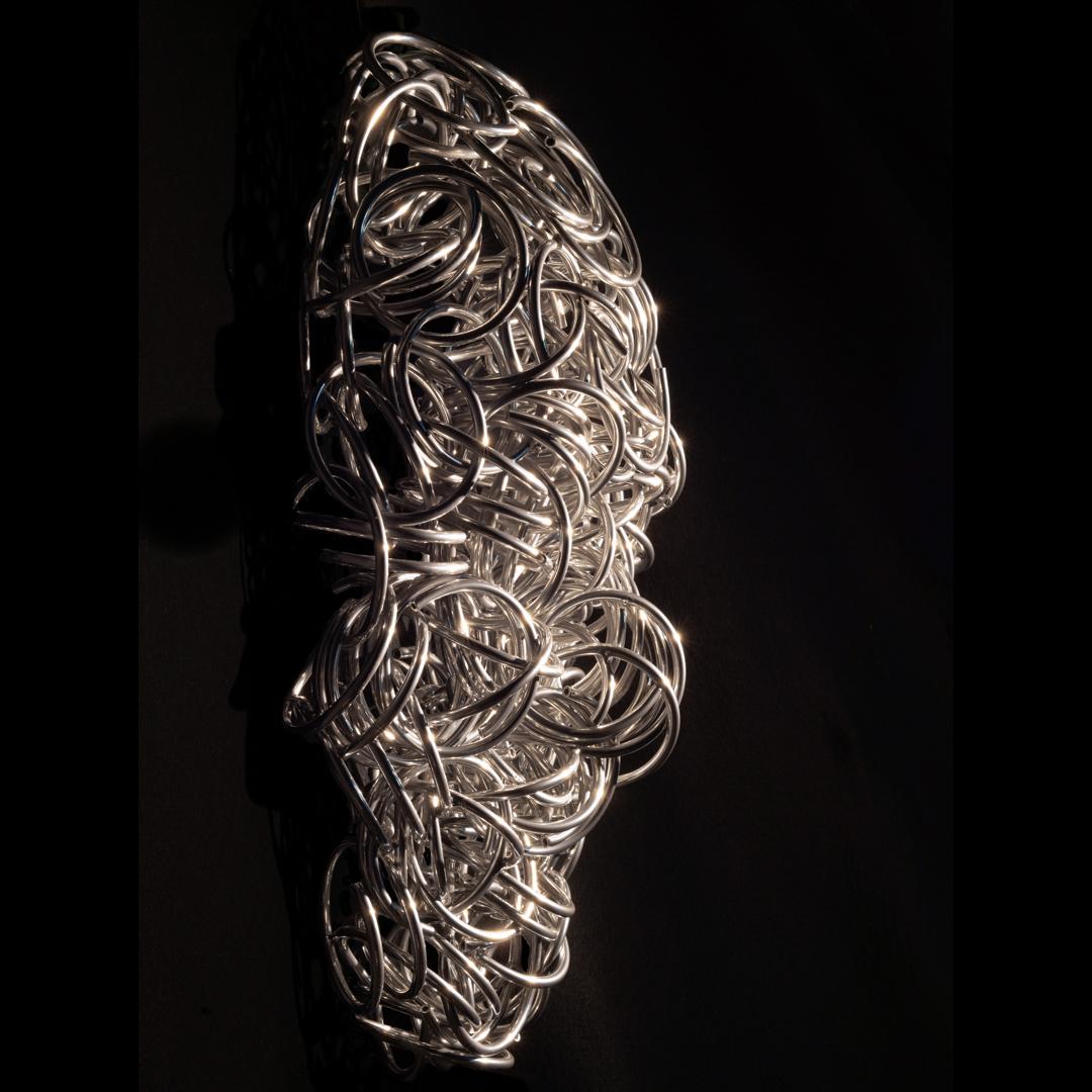 Uno dei principali scultori contemporanei del Canada, Dale Dunning continua a creare nuove opere originali dalla sua fonderia in Ontario. Forgiata da tubi di alluminio e rivestita con una finitura cromata riflettente, questa scultura da parete