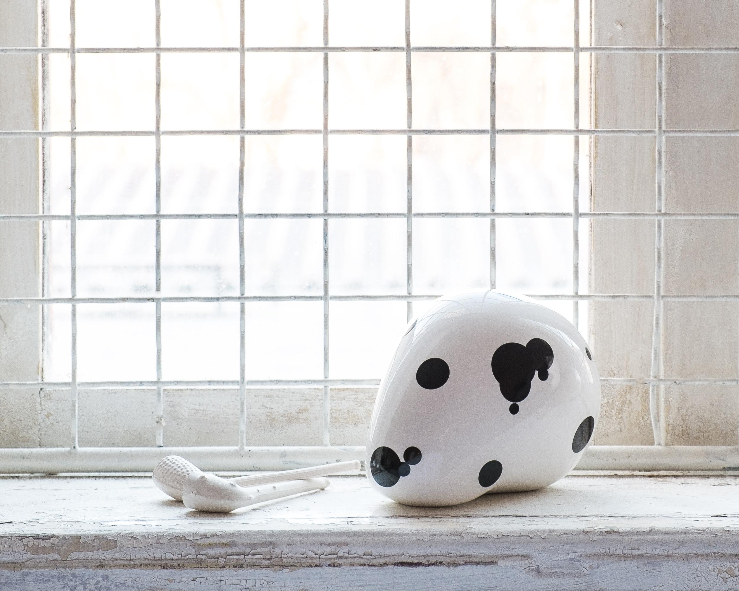 A shiny white porcelain figurine/sculpture titled Dalmation is a human skull redefined as a simplistic industrial form. Inglazed dots in different sizes imply the human's best friend since the Stone Age – the dog. Modeled in CAD, 3d printed, and