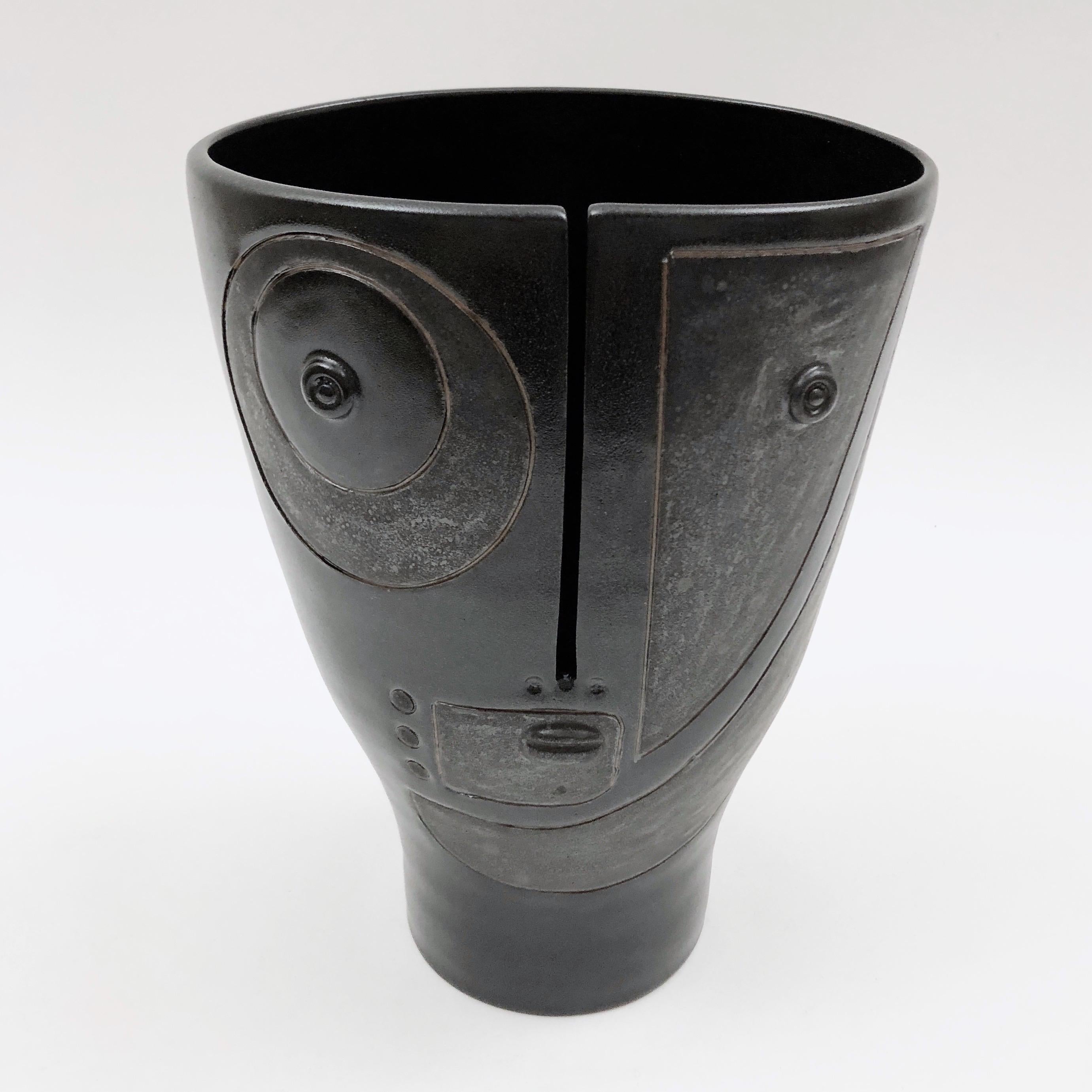 Figurative vase, called Idole, ceramic enameled in black and cloudy dark grey, decorated with a stylized visage and abstract designs incised front. 
One of a kind and exclusive handmade piece, designed and signed by the French artists and