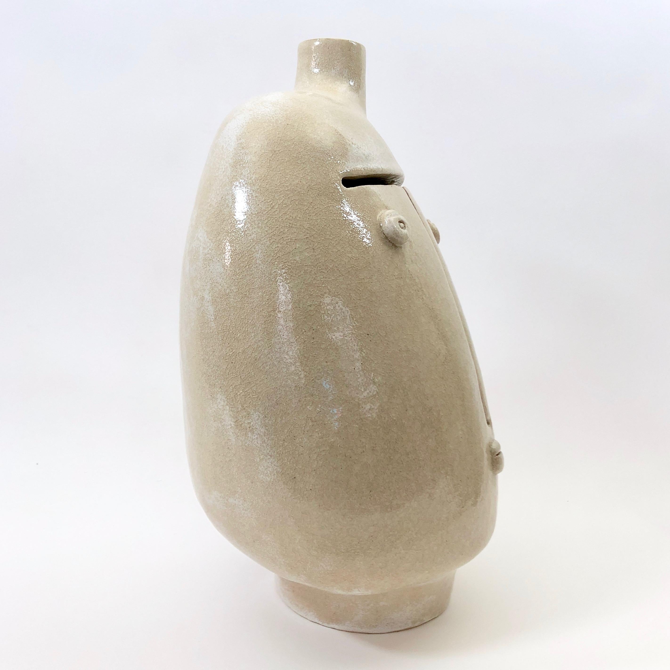 Important pottery sculpture, forming a table lamp base.
Ceramic glazed in cloudy beige spotted background, with a melted glass effect during glaze firing ; decorated with a figurative visage sculpted front and a small medallion engraved back. 

One