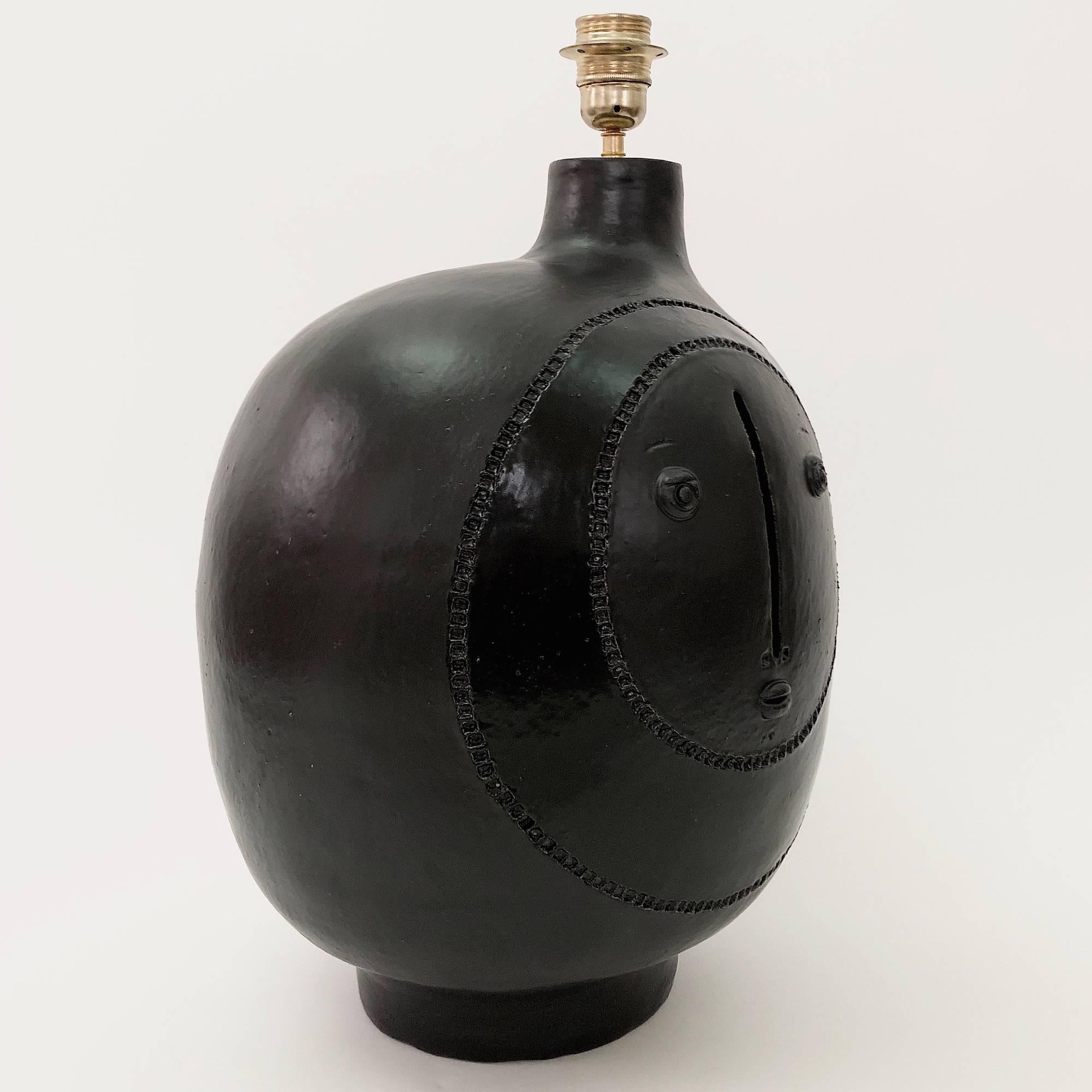Important sculptural pottery piece forming large table lamp base.
Ceramic glazed in matte and shiny black, decorated with a stylized visage engraved in front.
One of a kind handmade piece signed by the French artists ceramicists: Dalo. 

Dimensions