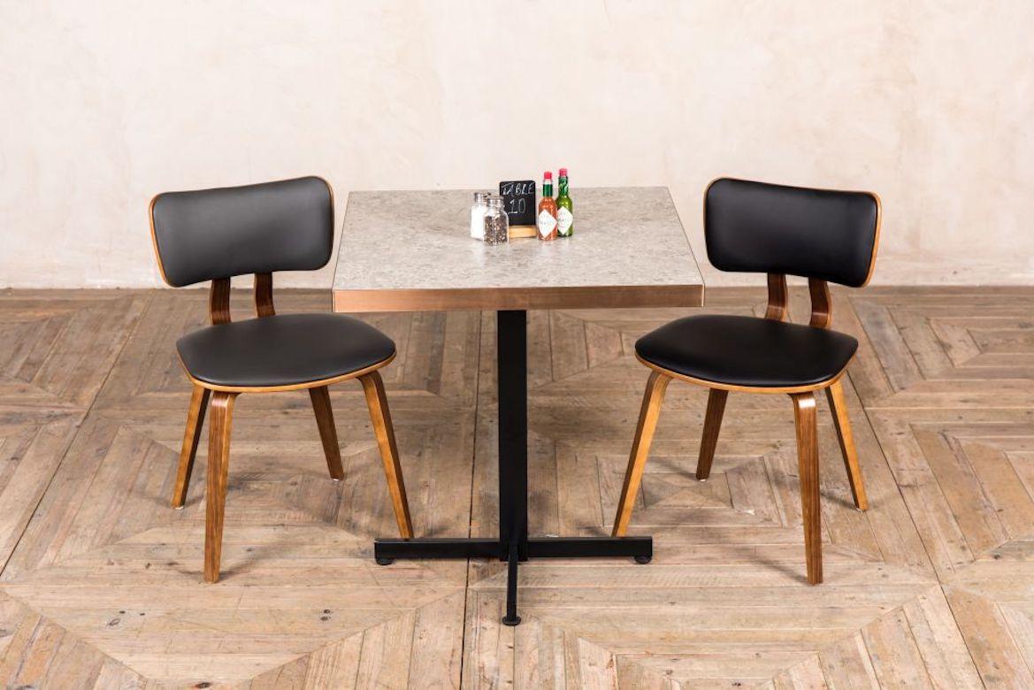 A fine Dalton restaurant dining chair, 20th century. 

With a faux-leather seat and back, the Dalton restaurant dining chair is handsome with a modern twist. The chair has a unique shaped wooden back and splayed wooden legs, which create a real