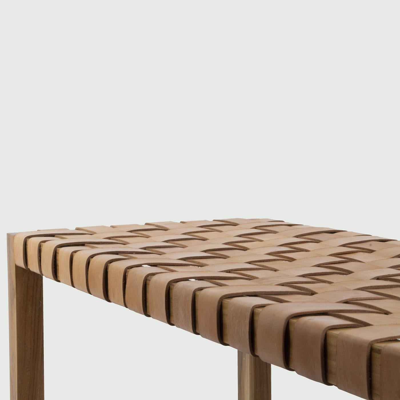 Entirely crafted by the expert hands of skillful artisans, this precious bench flaunts a clean silhouette blending prized leather and first-rate, solid teak. The braided design of the seat in brown leather adds a captivating aesthetic twist to the
