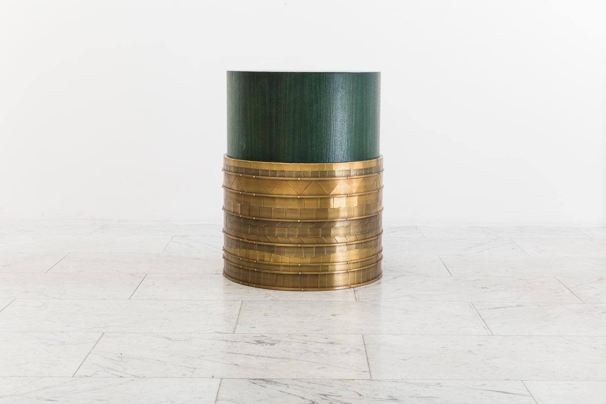 Damian Jones’s Rhoss Table functions perfectly as a side table or cocktail table. Its drum shaped form is sheathed in a mosaic pattern of hand-cut and laid brass “tiles.” Each tile has been patinated in varied colors and shades creating facets that