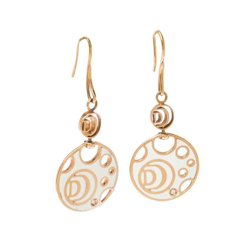 This pair of earrings from Damiani's Damianissima collection exemplifies minimal style with modern aesthetics. They are made from 18k rose gold and the hooks hold circular charms detailed with white ceramic, round cutouts, the 'D' symbol and a