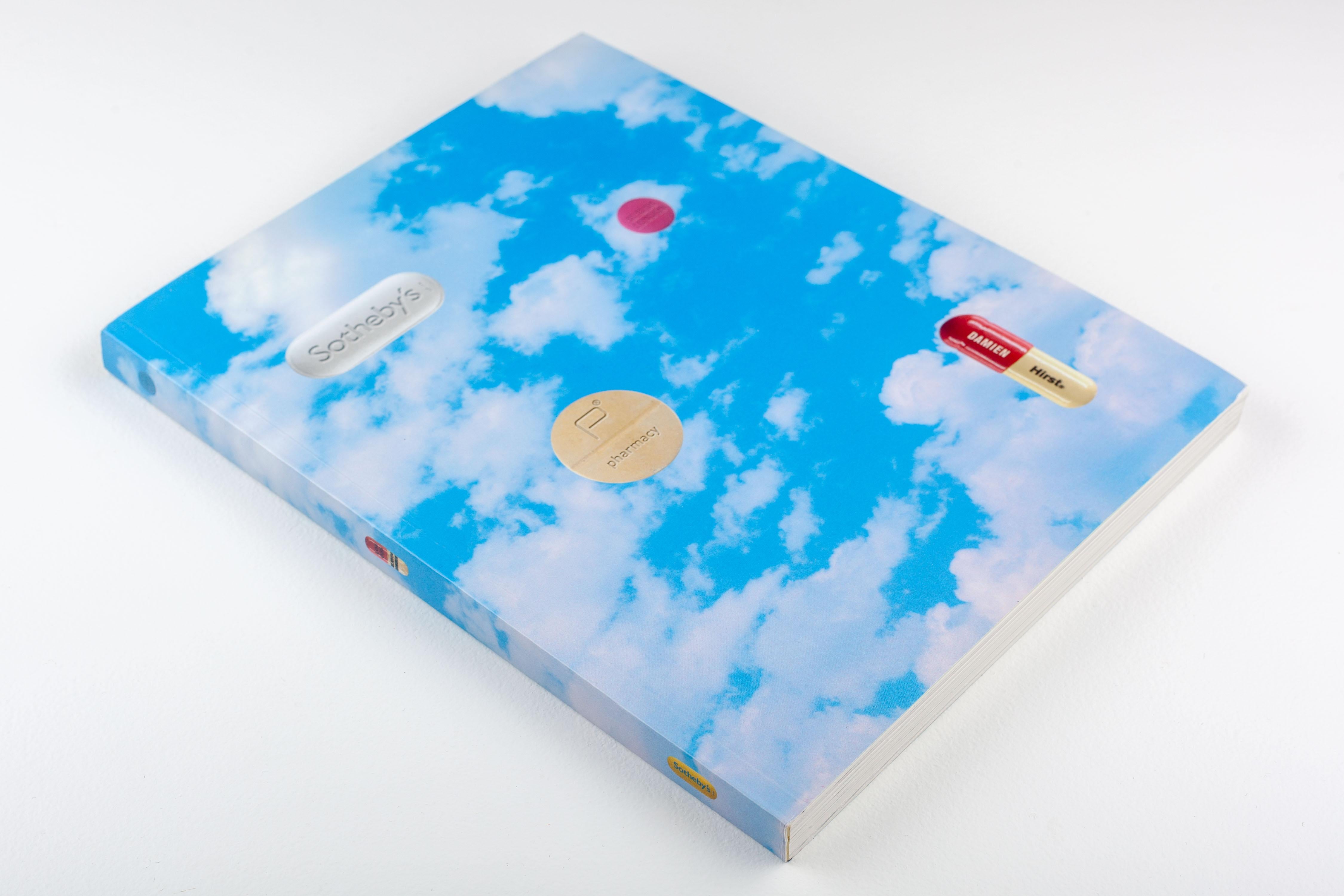 The book / auction catalog for Damien Hirst's restaurant, Pharmacy. The catalog is for the 2004 Sotheby's auction that featured the contents of the Pharmacy restaurant, which operated from 1997 to 2003 in the UK. Damien Hirst ully designed the