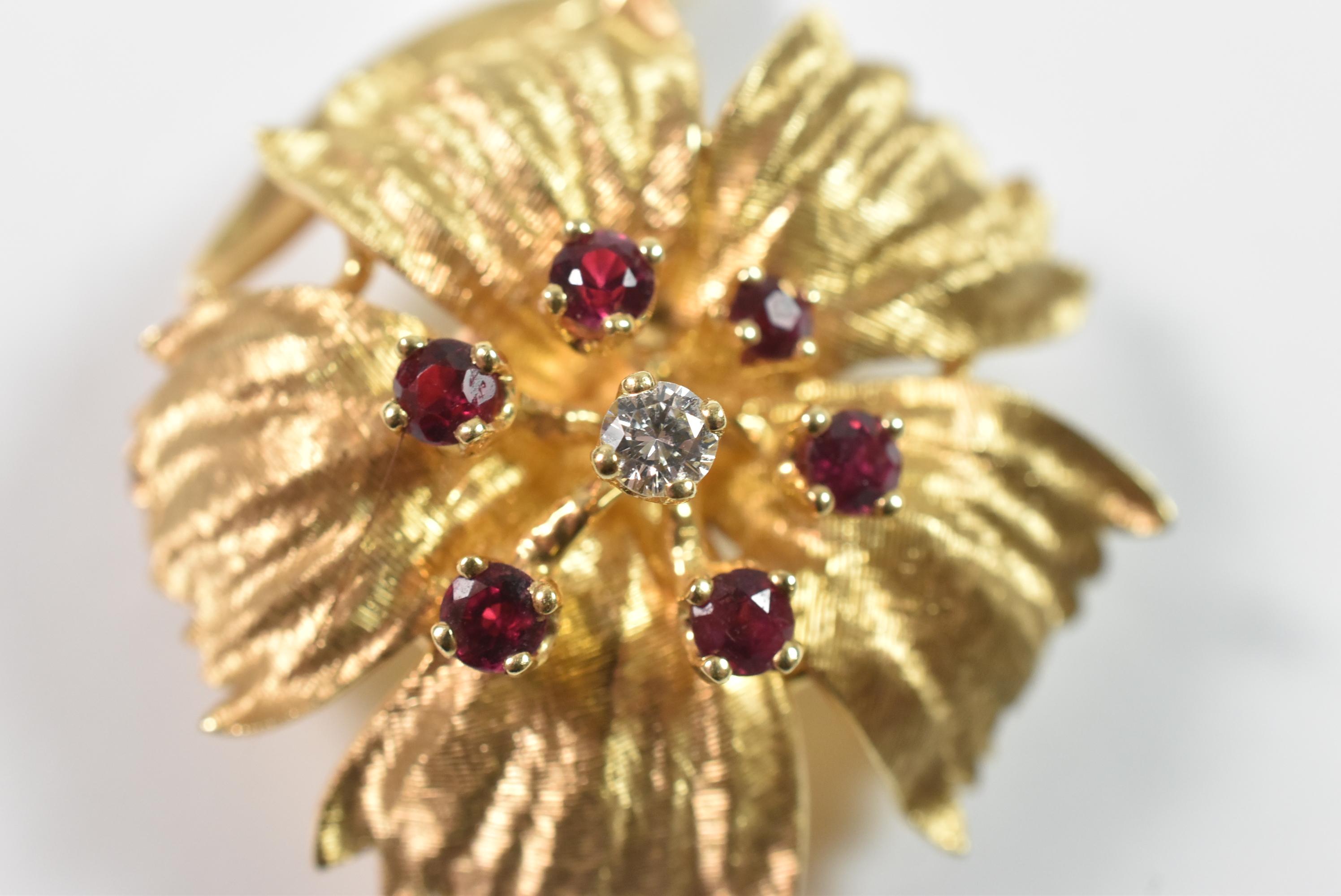 Gold floral pin stamped Dan Frere and 14K with a diamond in the center and 6 rubies. Very great condition. Dimensions: 1 7/8