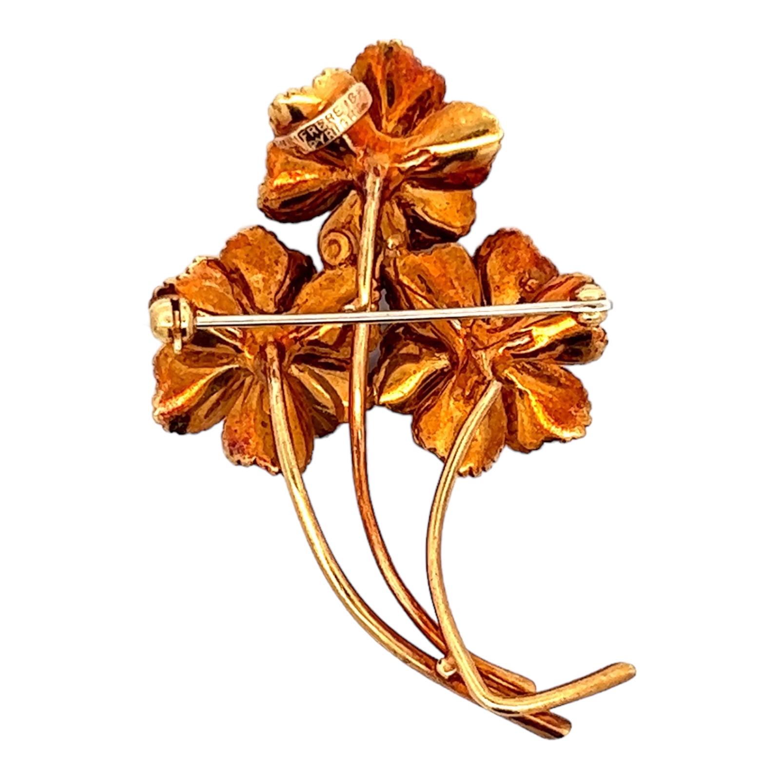 Beautifully crafted floral pin fashioned in 18 karat yellow gold. The brooch features 3 round brilliant cut diamonds weighing approximately .18 CTW. Natual sapphire, ruby, and emerald accents are added for color in the flowers. The brooch measures