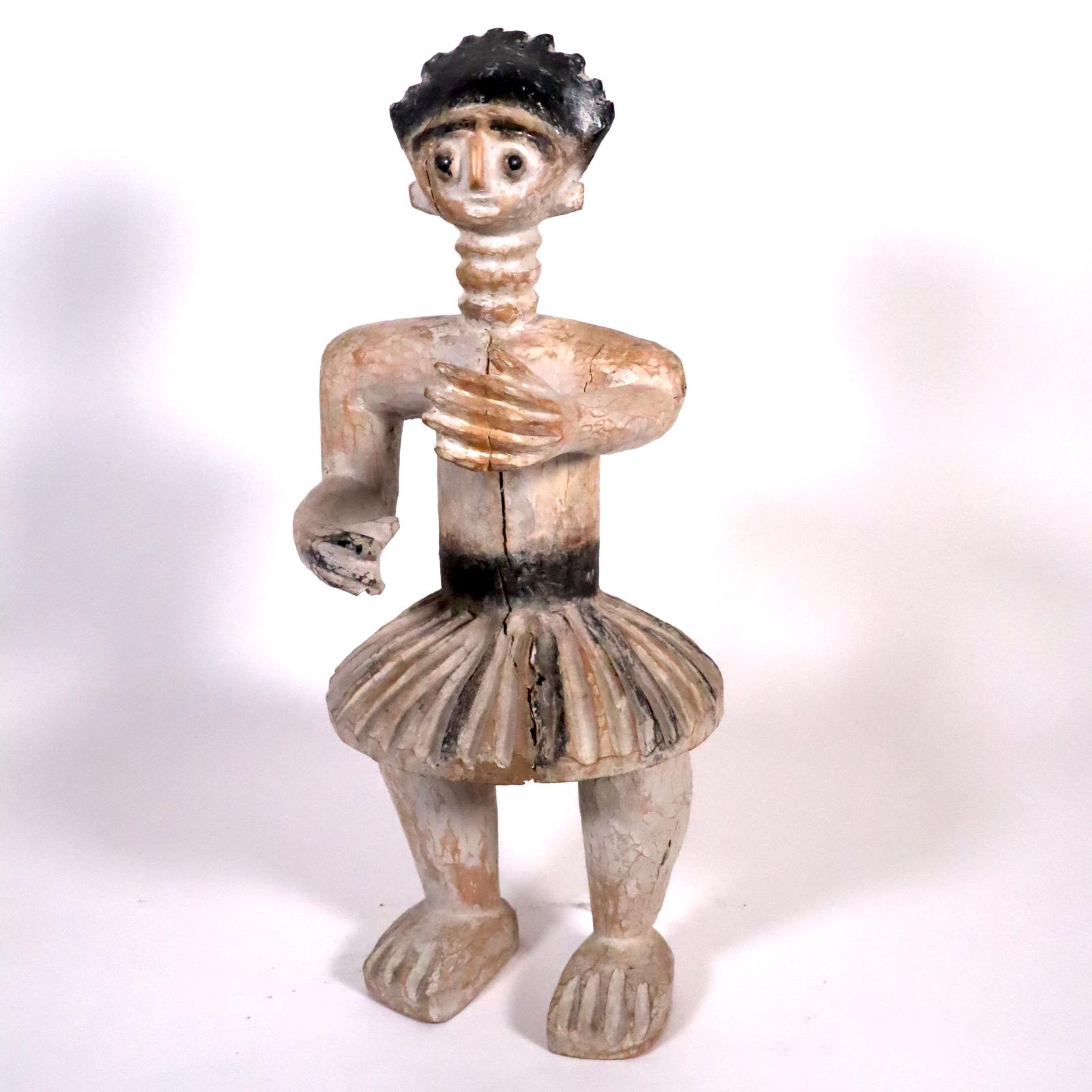 As a display during traditional drumming performances and ceremonies in Ghana, carved wood figures are placed near or in front of the drum ensemble. This figure is a male (genitals visible under skirt) posed with his right arm extended and his right