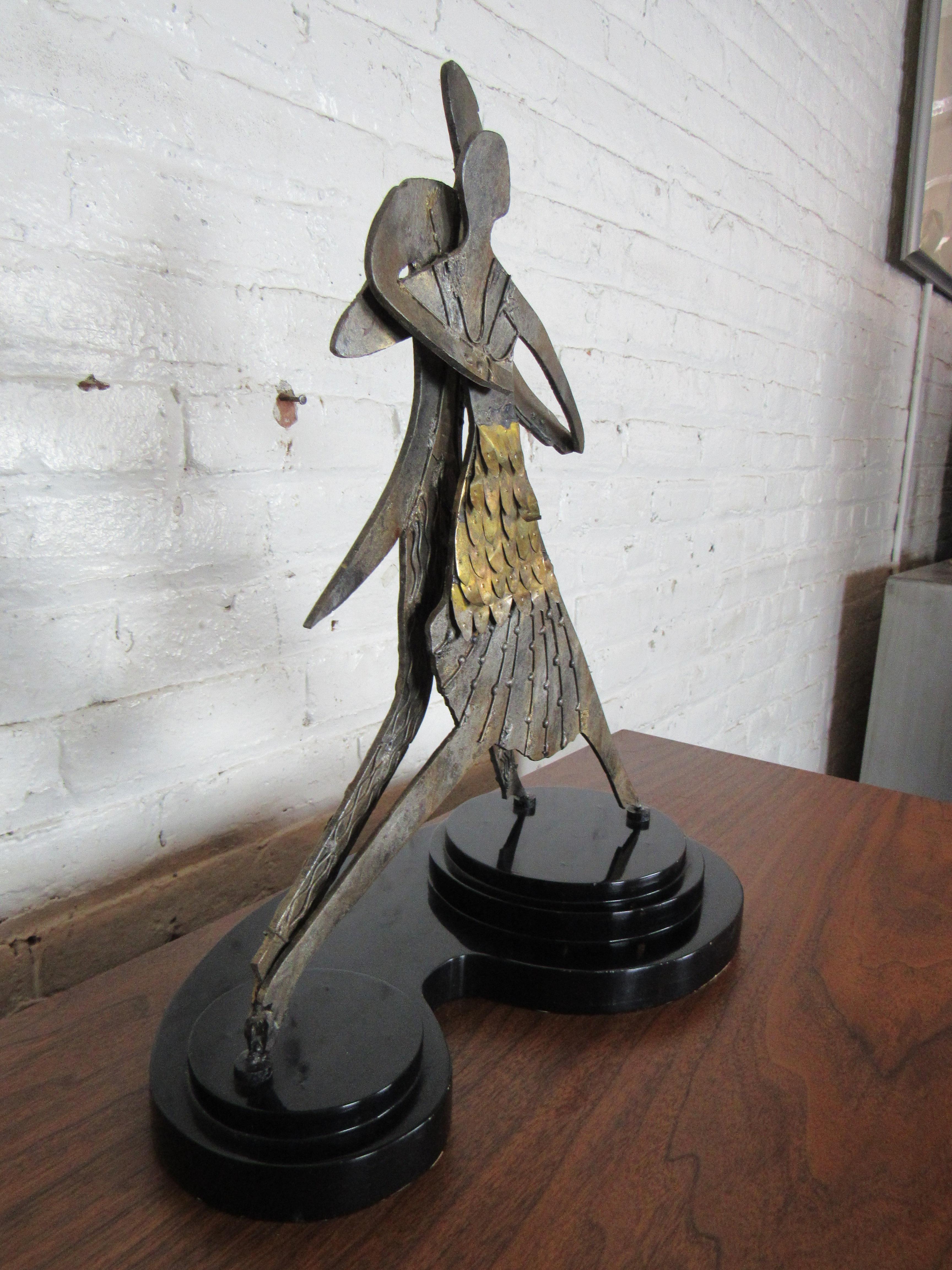 Une paire de personnages dansant est représentée dans cette sculpture vintage de table. Une base en plastique lourd avec du velours sur son fond permet de l'utiliser dans n'importe quel endroit comme un grand objet de décoration. Veuillez confirmer