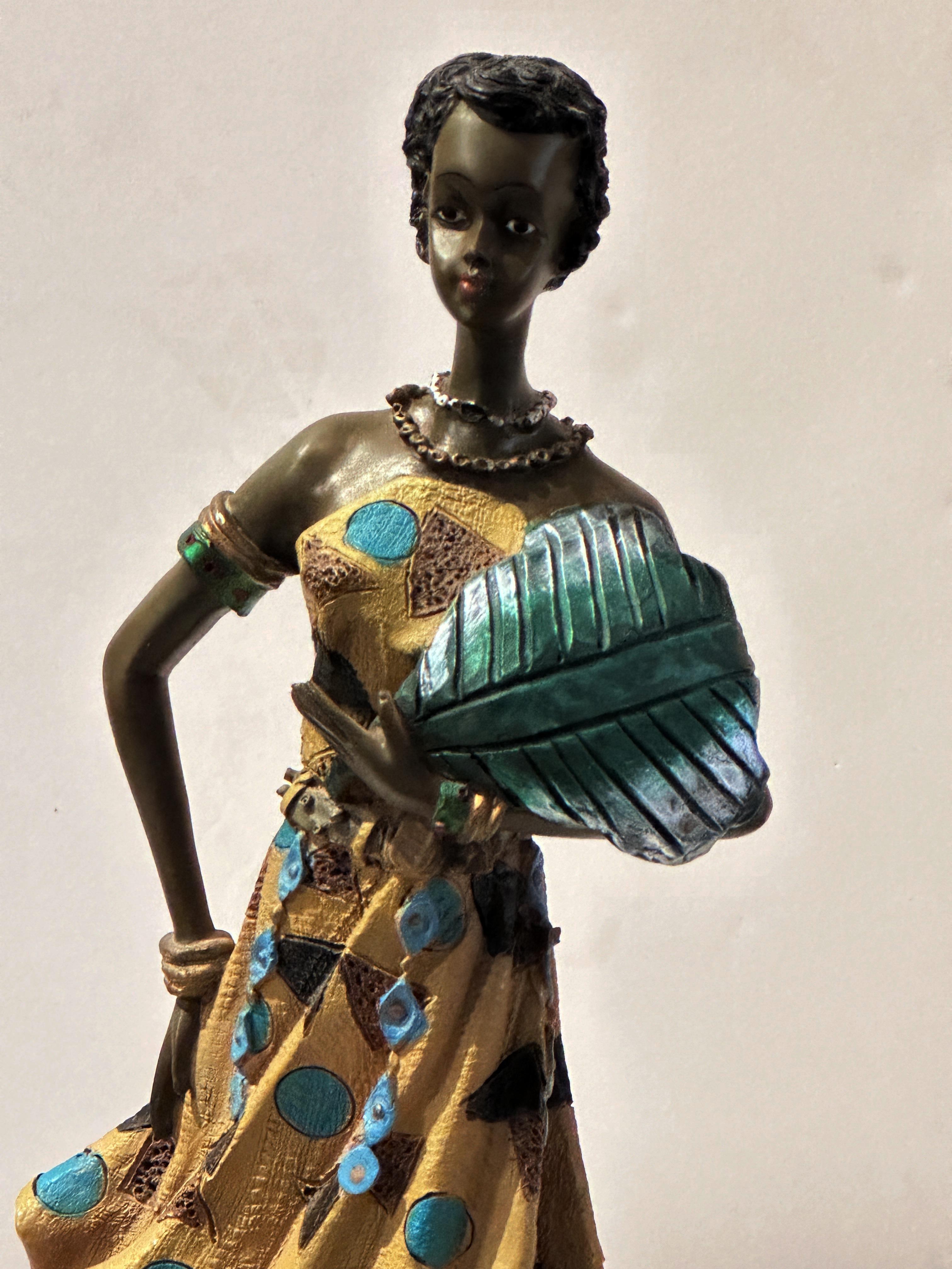 This African figure sculpture, posing with her large leaf fan, could be titled 