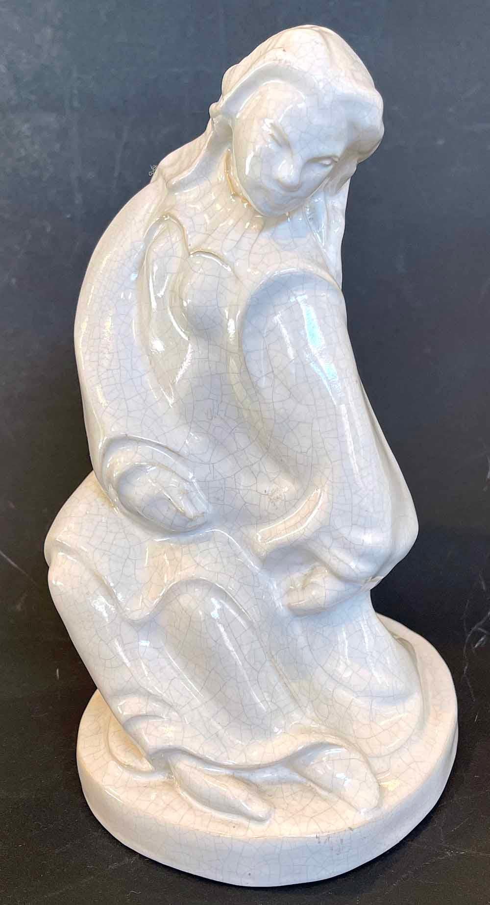 Única y encantadora, esta escultura de cerámica de los años 30 representa una figura femenina danzante, con su larga túnica arremolinándose a su alrededor mientras se desplaza por el espacio, con la cabeza mirando hacia abajo y las manos a los