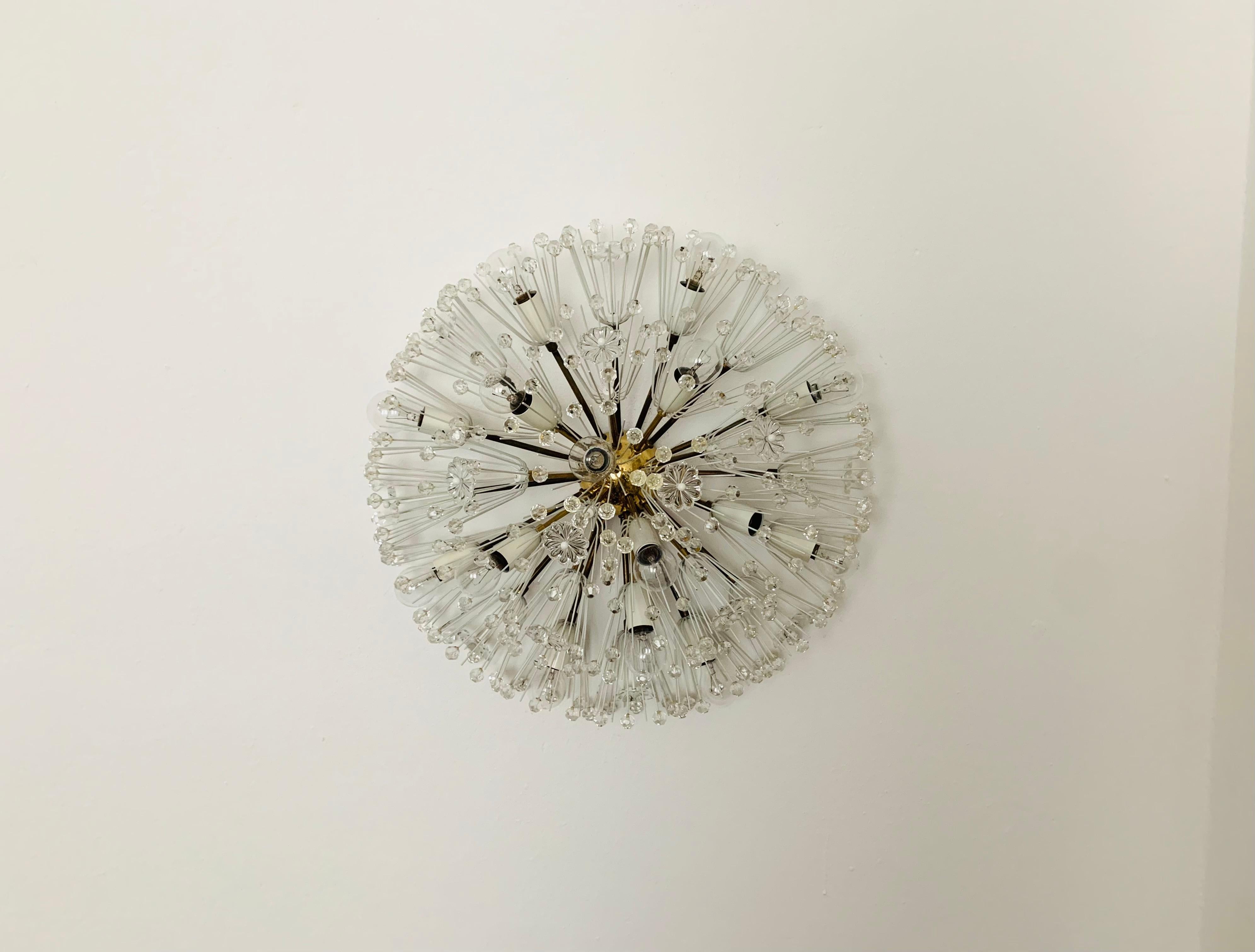 Very large dandelion wall lamp or ceiling lamp from the 1950s.
The lamp with its lavishly decorated flowers and brass details has a very luxurious look and sparkles particularly beautifully.
The design and the materials used create a great