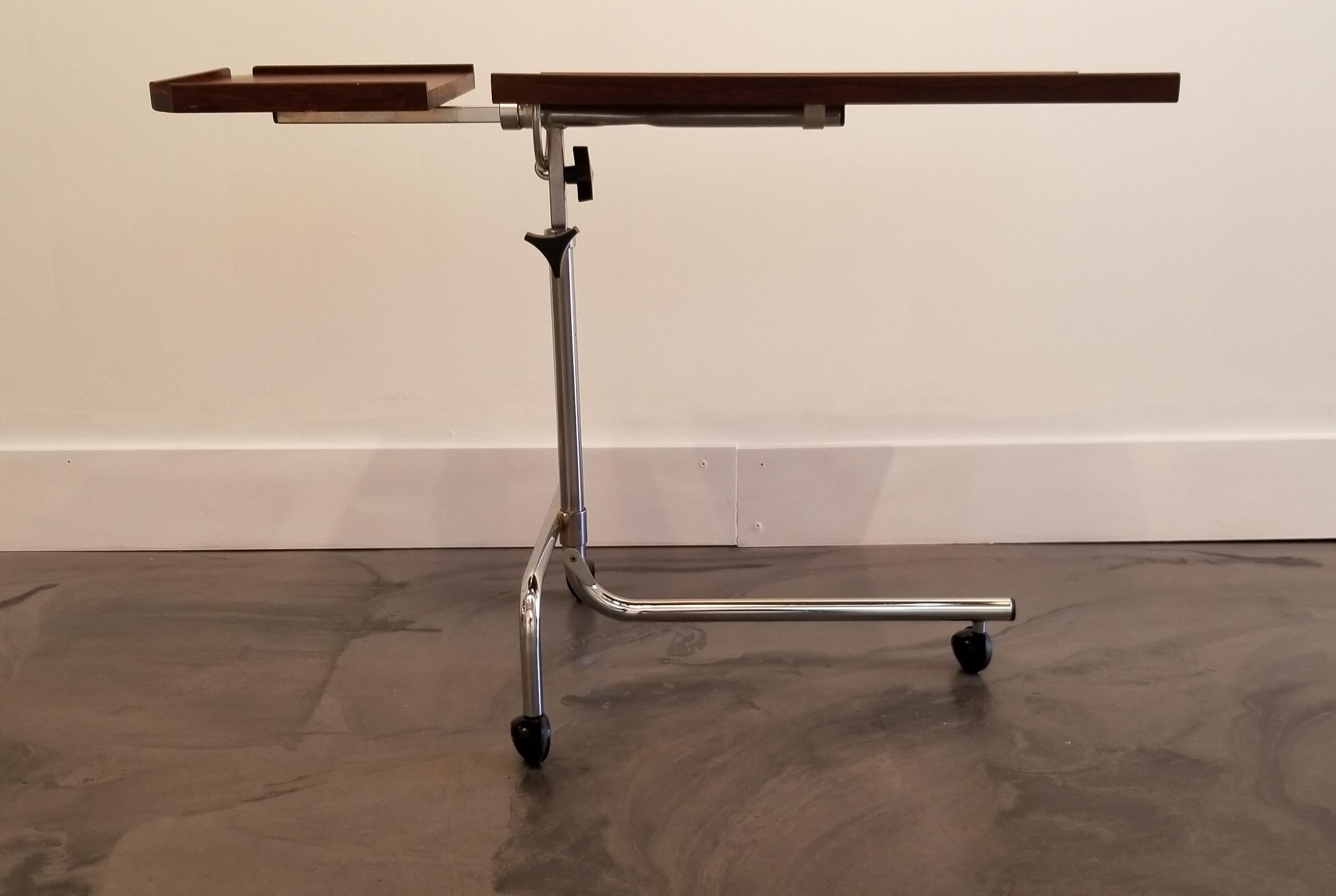 A Danish Modern adjustable table made of rosewood and polished chrome. Top tilts 90 degrees and has height adjustment from 25 inches to 34 inches in height. Will make a nice bedside, end table, TV table or work table. Small side table is removable.
