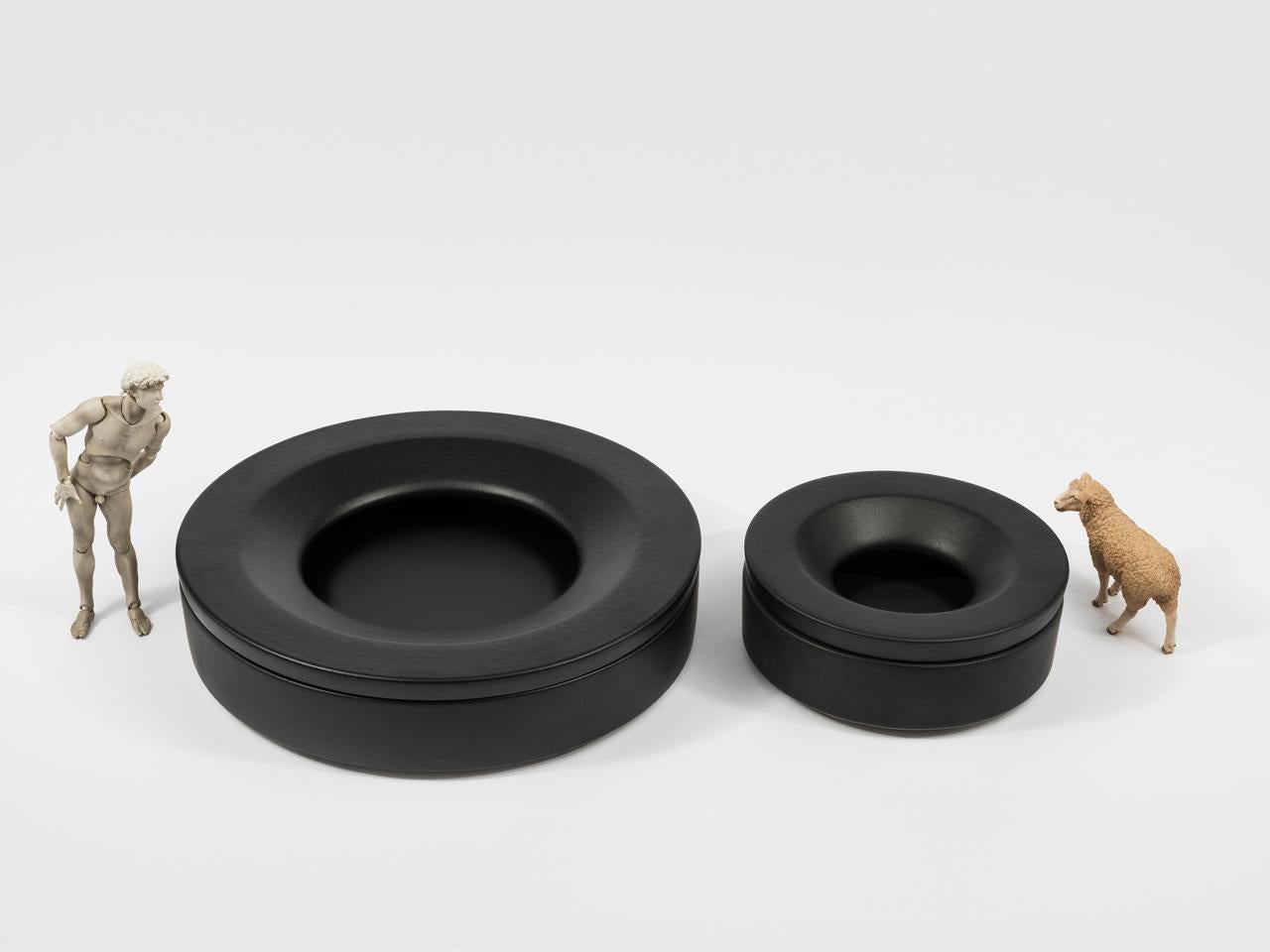 Large Black Barbados is a glazed ceramic ashtray made up of two parts: a circular base and a ring shaped lid that fits on top and hides part of the contents. The simple, pure geometry of the design give Barbados a distinctive aura that almost turns