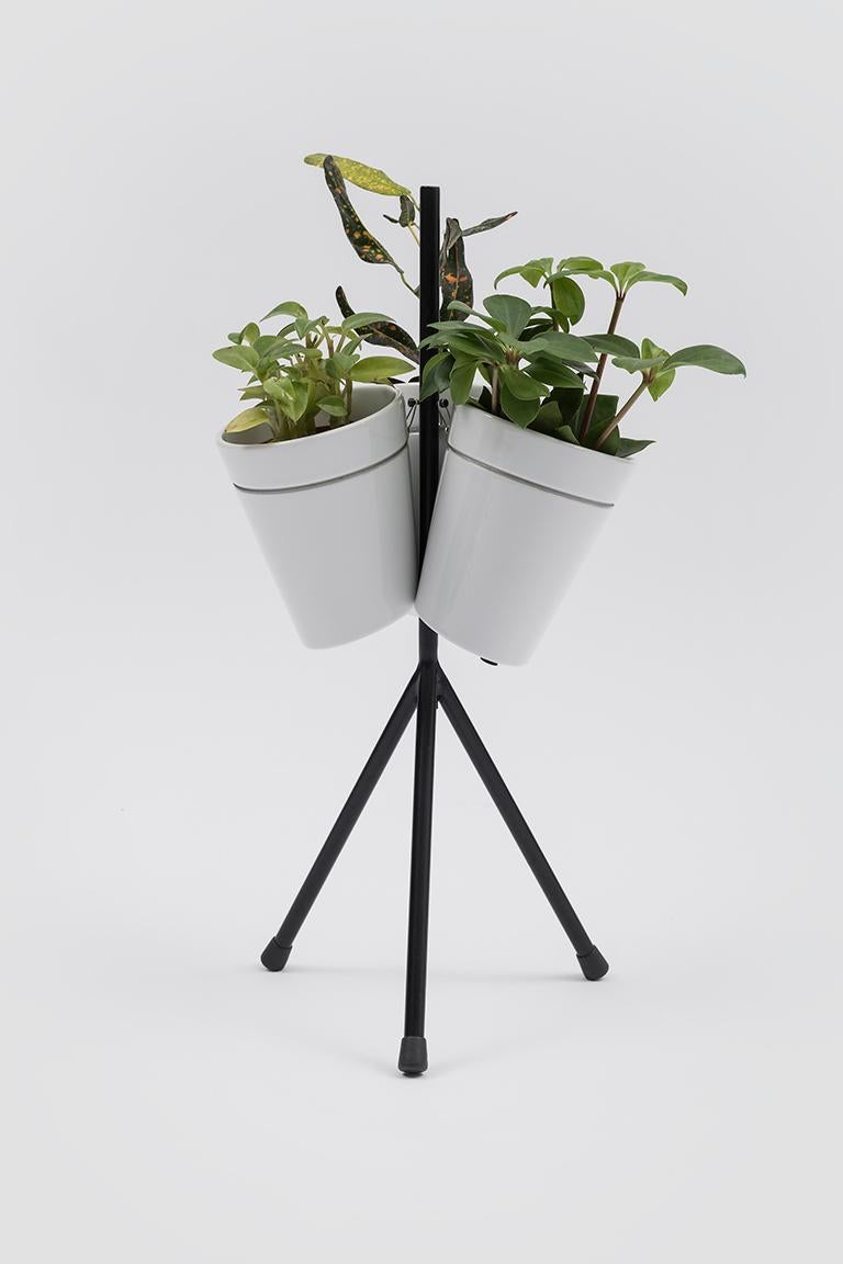 Window garden table is part of the collection of vases designed by BIG for hydroponic cultivation. Three high-pressure cast white porcelain vases are mounted on a thin metal tripod base. In its own innovative way, the piece represents a