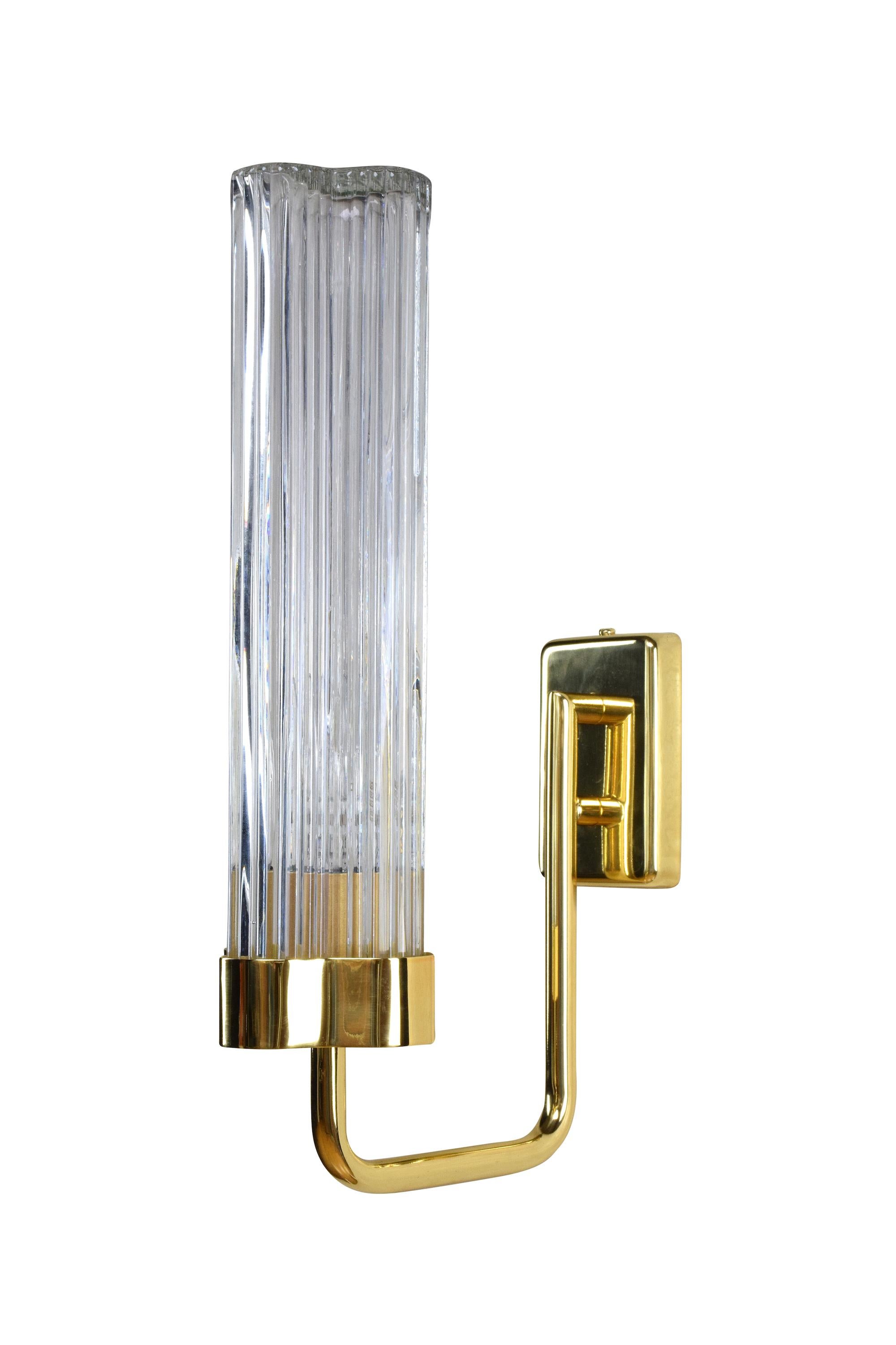 This wall light is designed with a slender brass structure and a textured glass shade with vertical lines morphing into an organic shape. This model comes with a single fixture, but a double fixture is also available in our studio.

Light source: