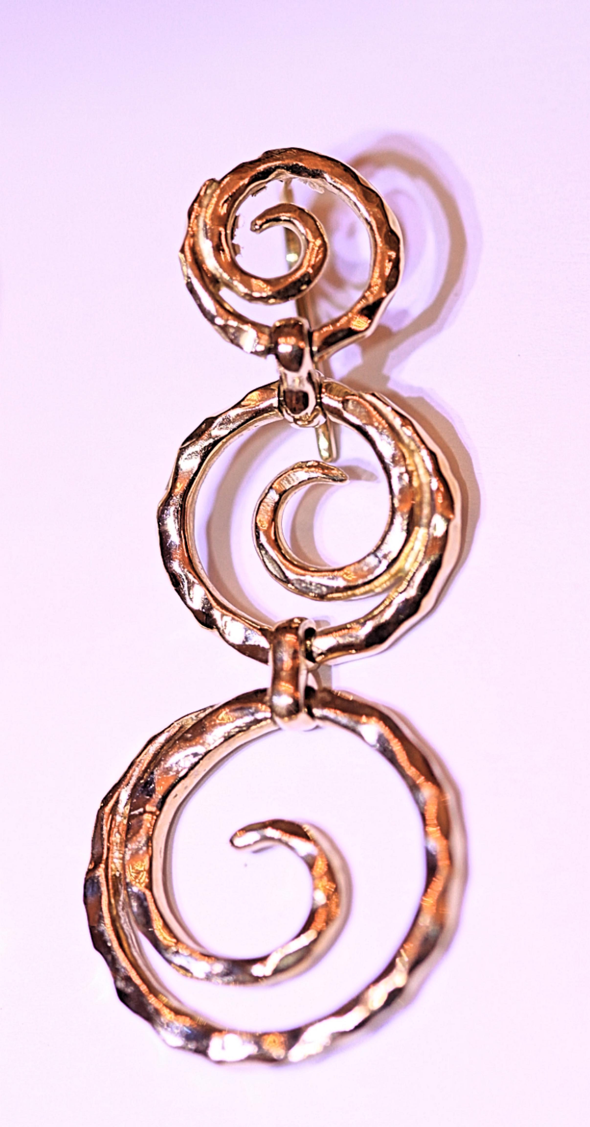 An exquisite pair of 18 karat yellow gold earrings.  The earrings were designed by Sal Praschnik and he calls them the wave design.  The earrings consist of three beautiful circles that dangle 2 inches long and they are 3/4 inches wide.  The circles