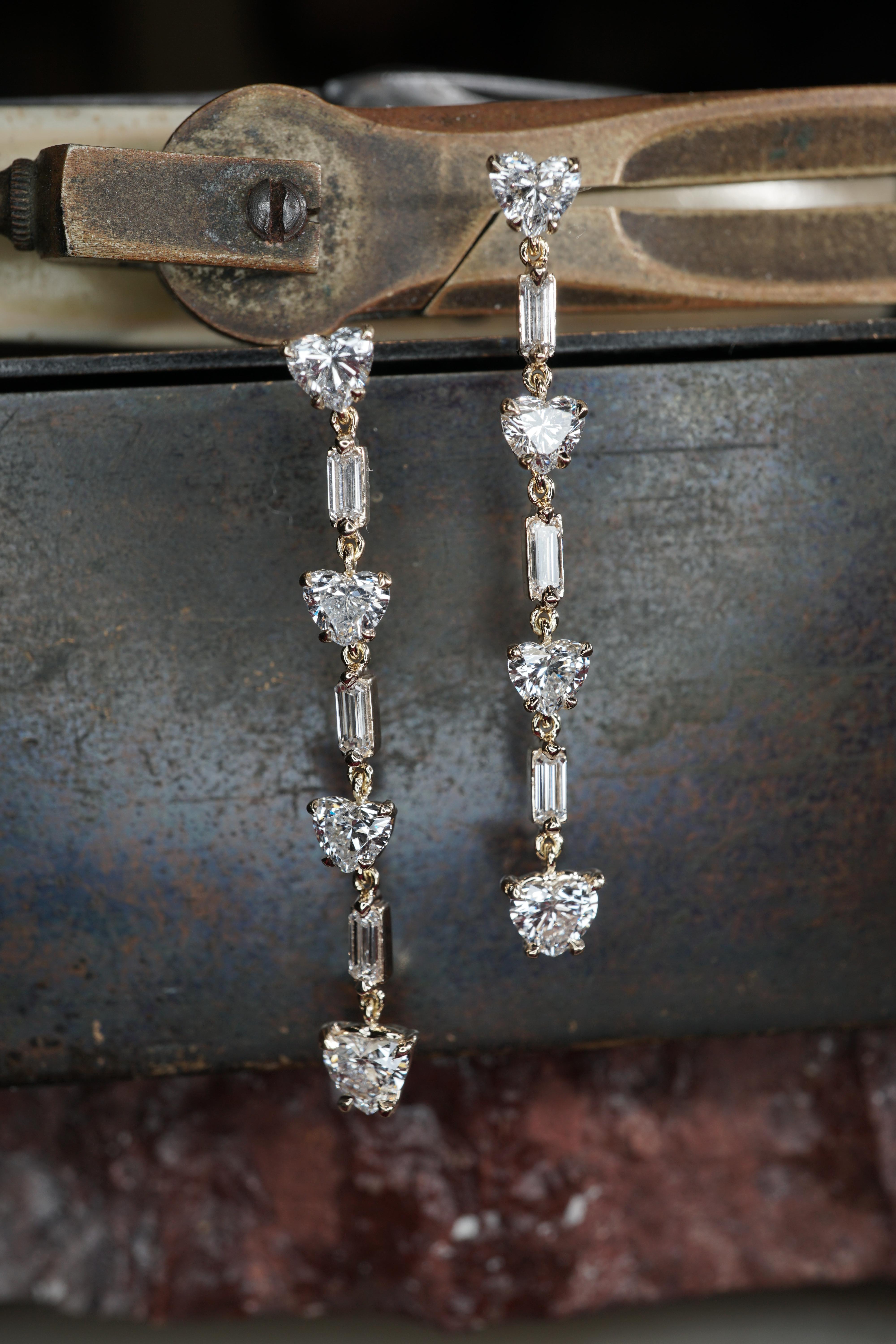 Alternating heart and emerald cut diamonds drop dangling earrings, 1.80 carats total weight. These earrings are set in 4 prong basket in 14K Yellow Gold.

This piece can be customized with any metal, diamonds, and stone shape and size. The