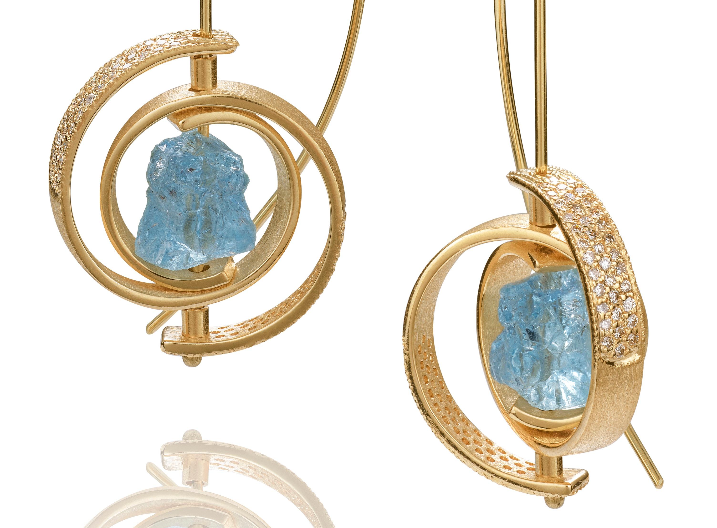 The award  winning Ceres Earrings from the Orbit collection in 14k yellow gold, with hammer- cut aquamarines and 35 tiny pave diamonds on each spiral (70 per earring) that surrounds the aquamarine. The earrings hang approximately 2