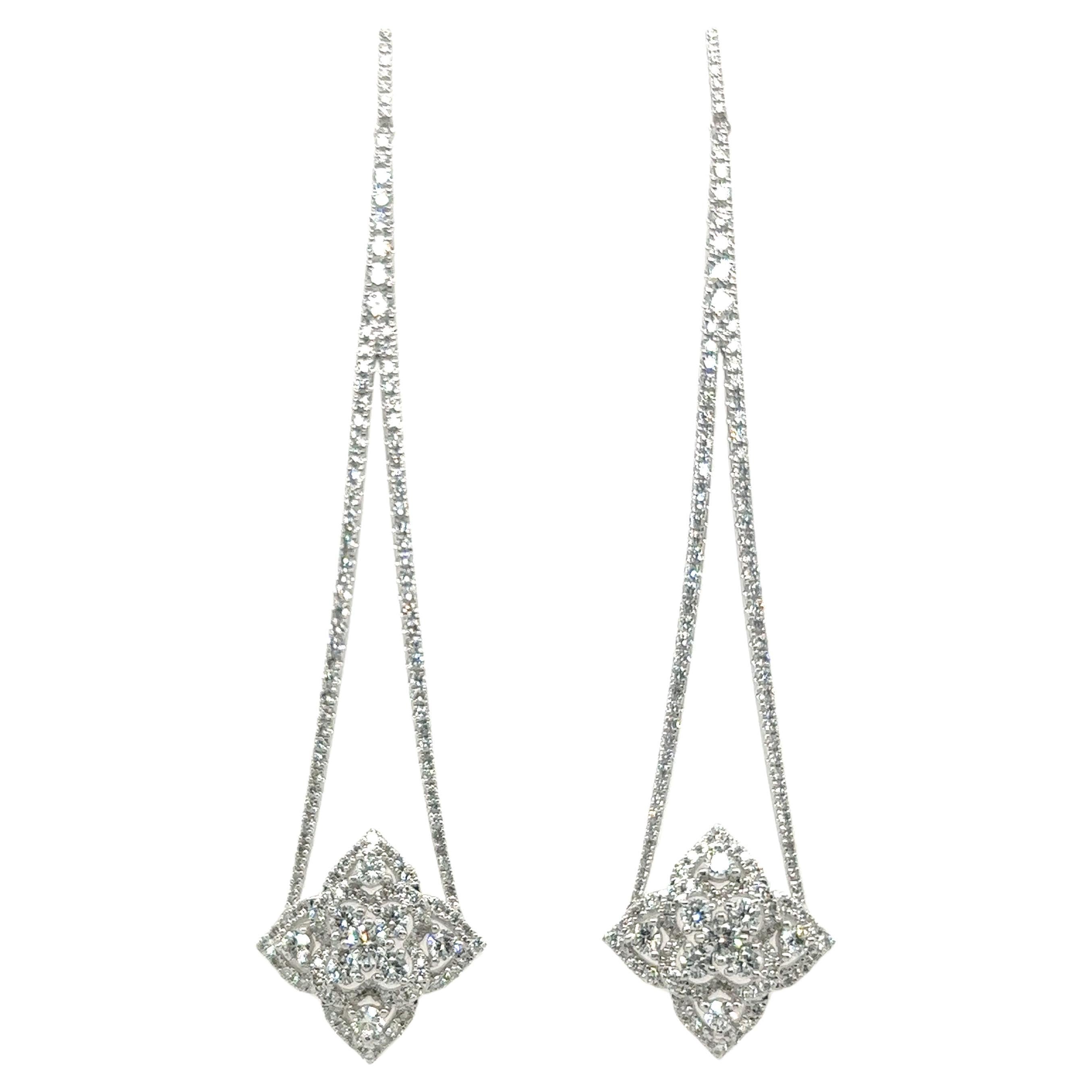 These exquisite dangle earrings with diamonds in 18 Karat white gold embody a harmonious blend of elegance and architectural inspiration. 

Their design seems to draw inspiration from the delicate beauty of the Gothic cathedrals, forming a